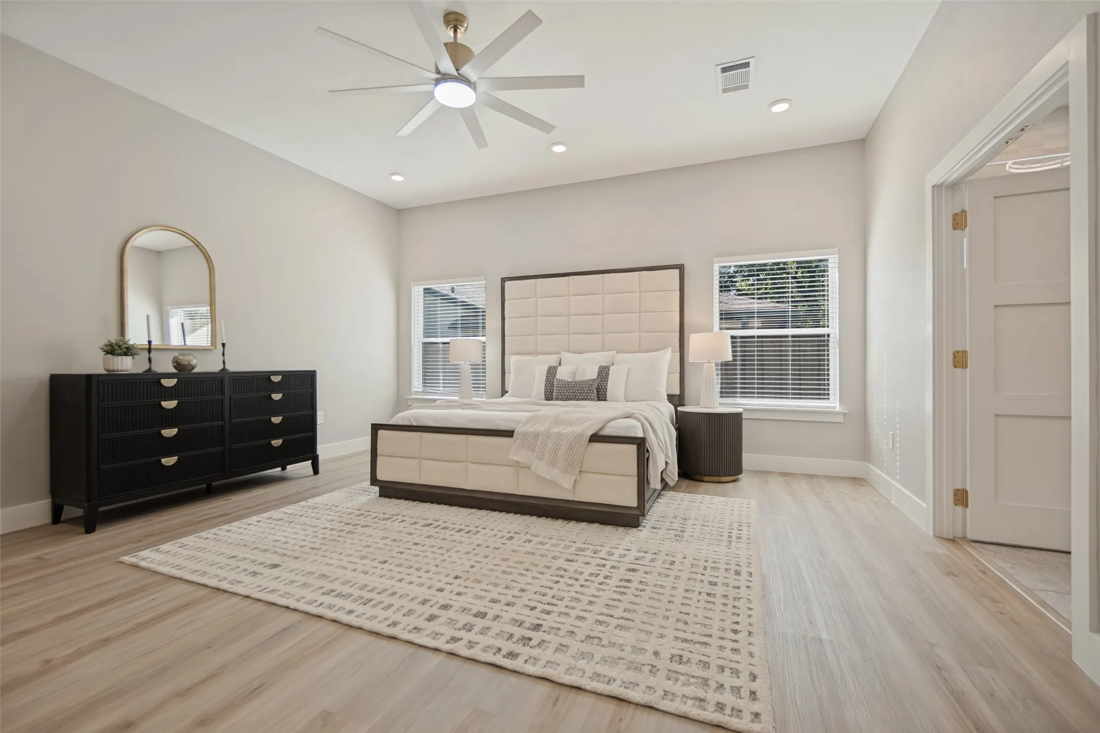 Light wood-finish flooring with recessed lighting and a ceiling fan