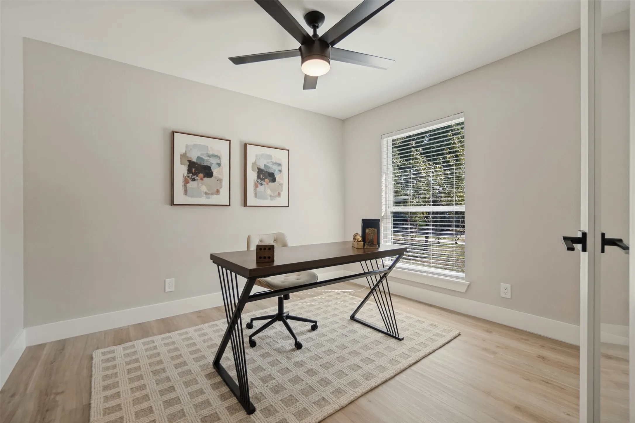 Wood-finish flooring, a window with horizontal blinds, and a ceiling fan with integrated lighting