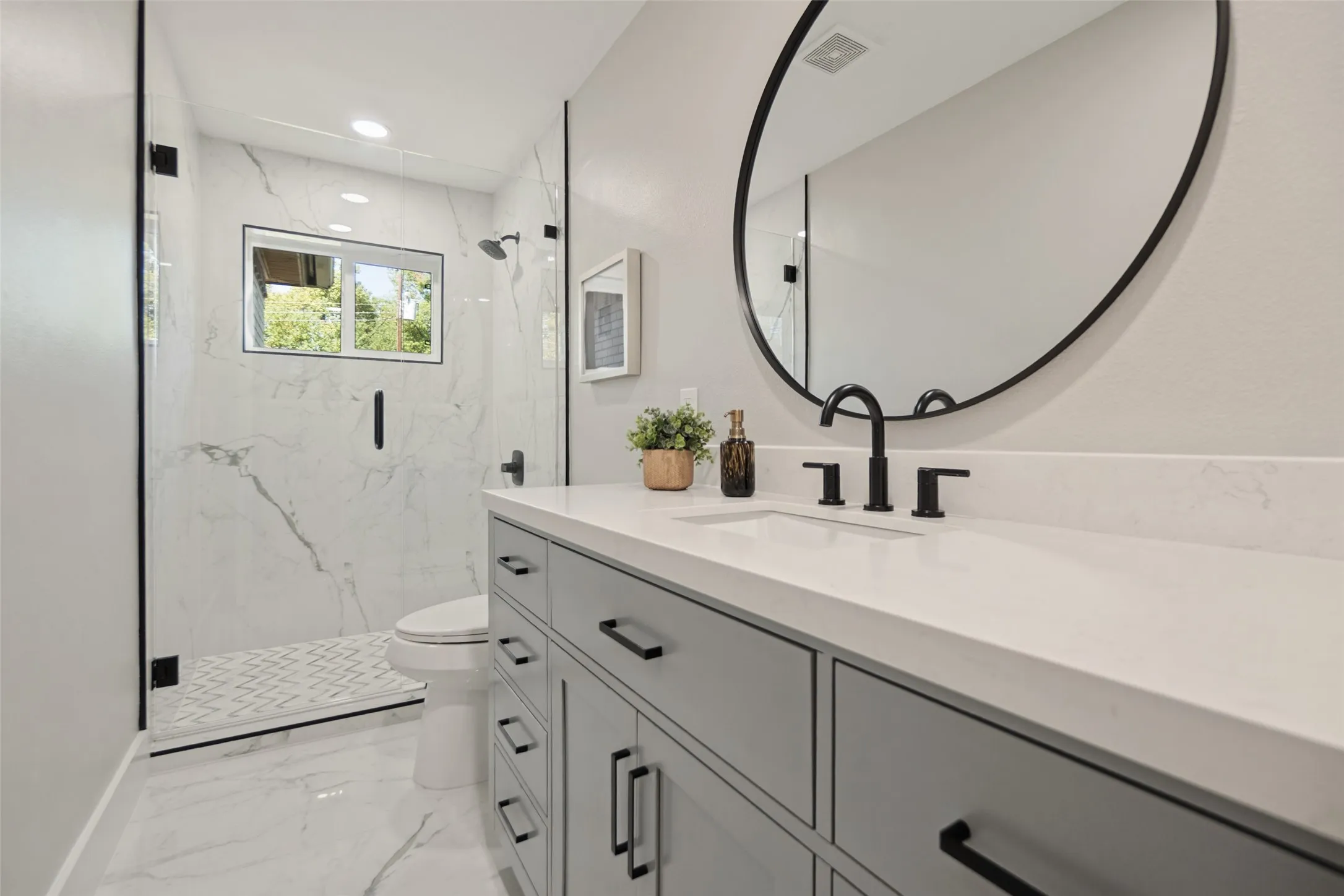 Vanity with solid surface countertop, matte black fixtures, and an oval mirror