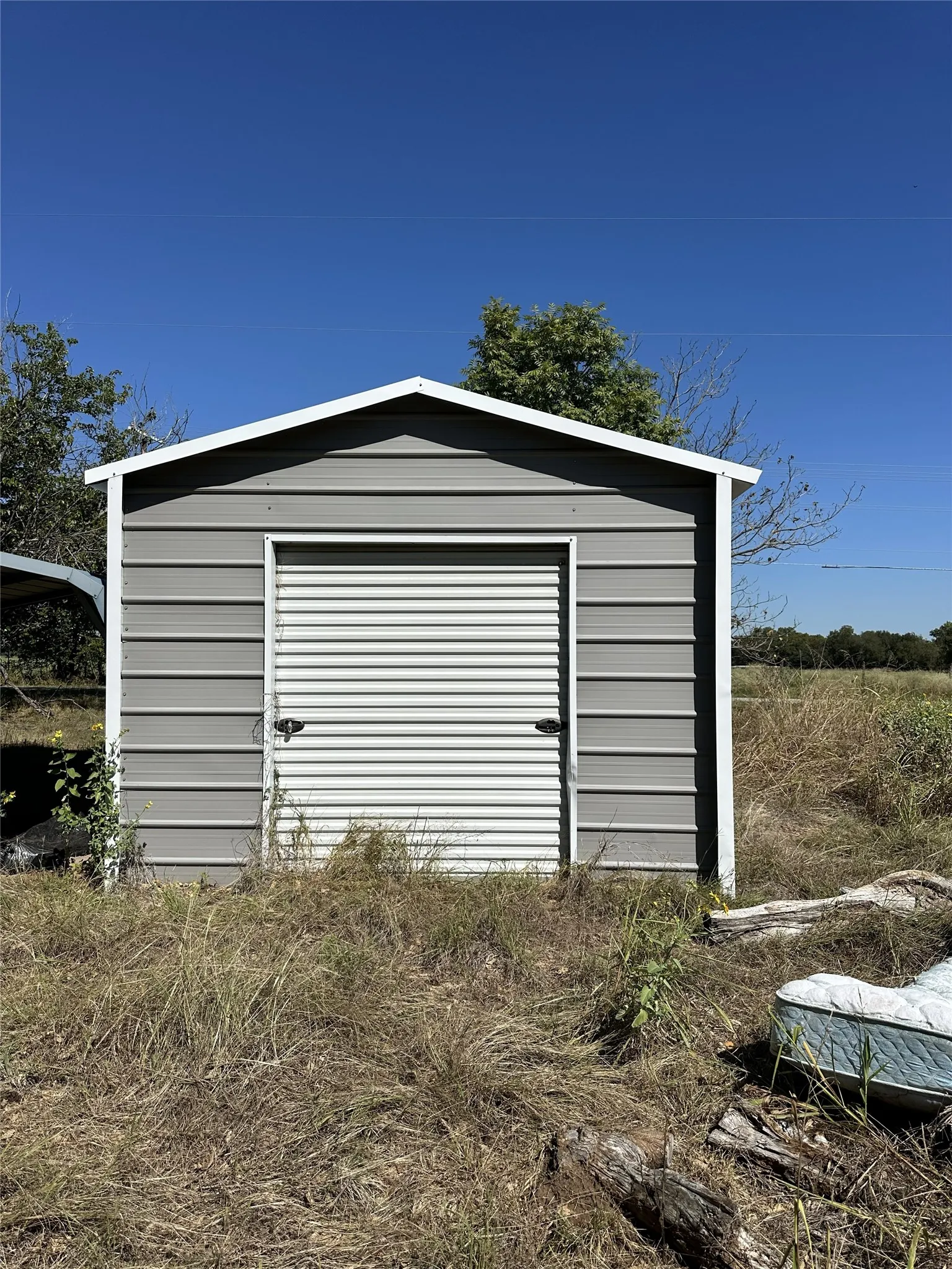 Metal storage shed featuring a gable roof and roll-up door