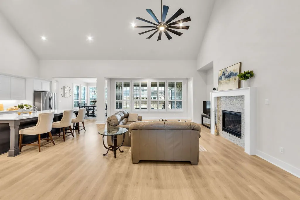 Vaulted ceilings with a ceiling fan, recessed lighting, wood-finish flooring, and a fireplace with a decorative tile surround