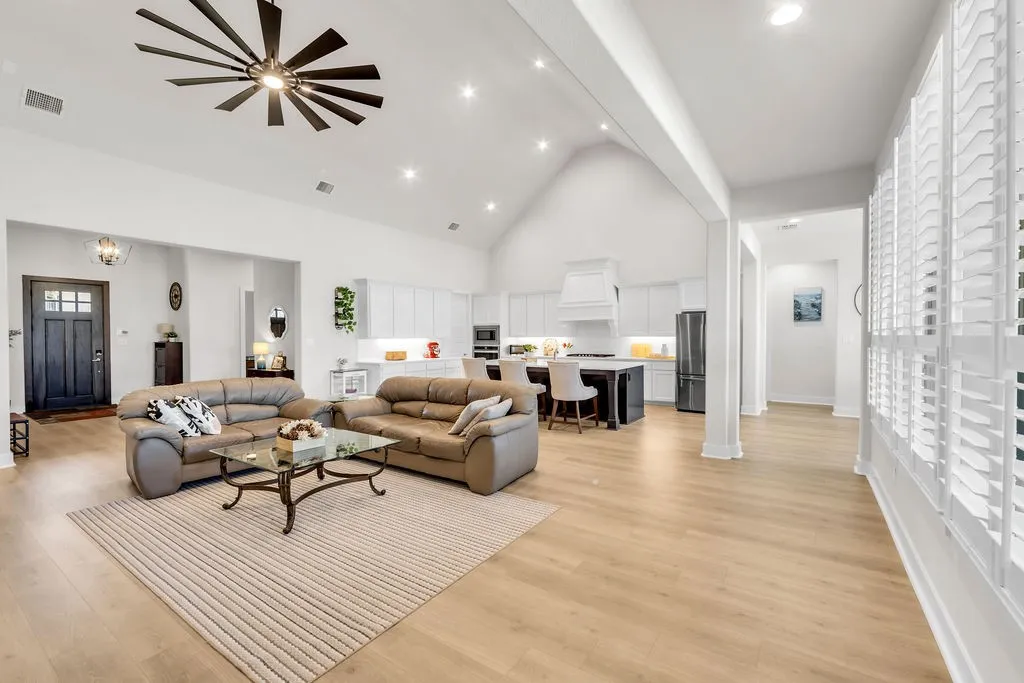 Vaulted ceiling, recessed lighting, wood-finish flooring, plantation shutters, and a modern ceiling fan