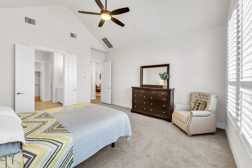 Vaulted ceiling with a ceiling fan, white plantation shutters, and carpet flooring