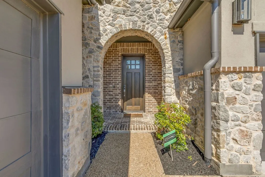 Stone and brick exterior with an arched entryway, leading to a dark wood-paneled door