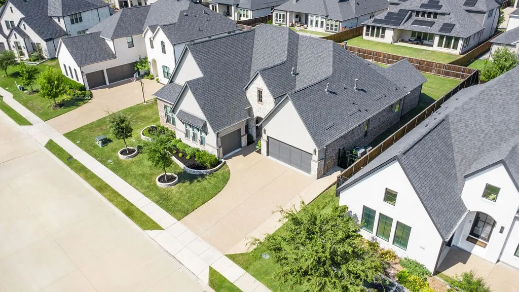 Two-story residence featuring a dark gray shingle roof, brick and light-colored siding exterior, and an attached two-car garage