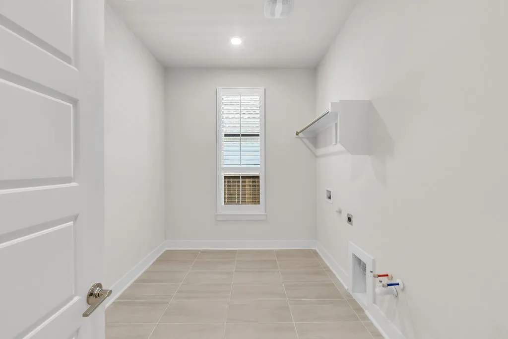 Laundry room with a single window, overhead lighting, and a built-in shelf with hanging rod