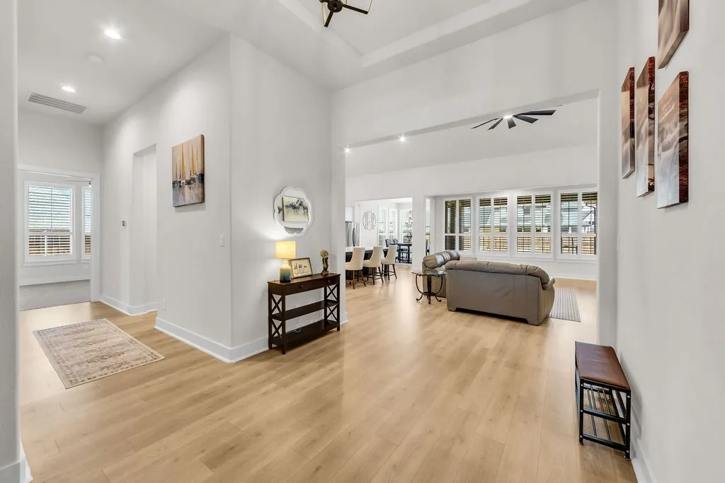Expansive open-concept living area featuring light wood-finish flooring, recessed lighting, and a ceiling fan