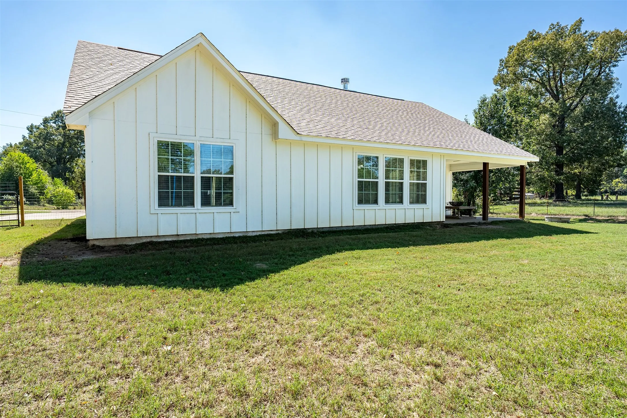 White board and batten exterior with multiple windows and a covered patio