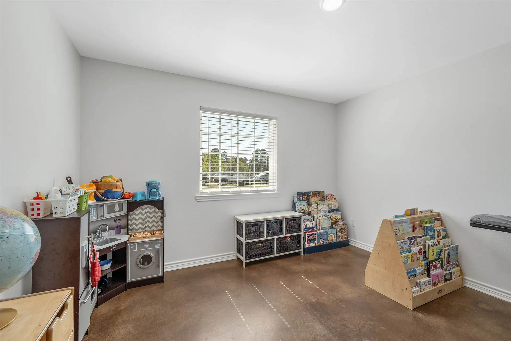Recessed ceiling lighting, a single window with blinds, and stained concrete flooring