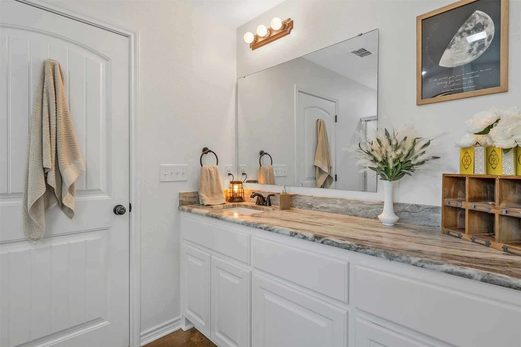 White painted wood cabinetry with brushed nickel hardware, a rectangular undermount sink, and a stone countertop