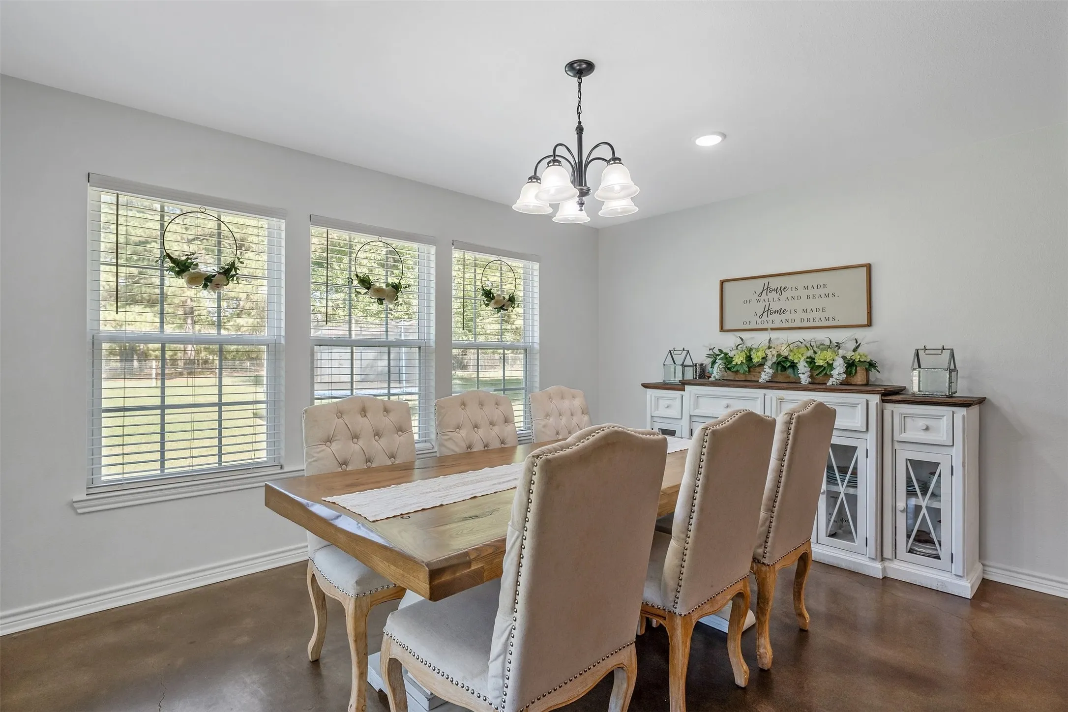 Recessed lighting, dark wood-finish flooring, multiple windows with blinds, and a traditional chandelier with frosted glass shades