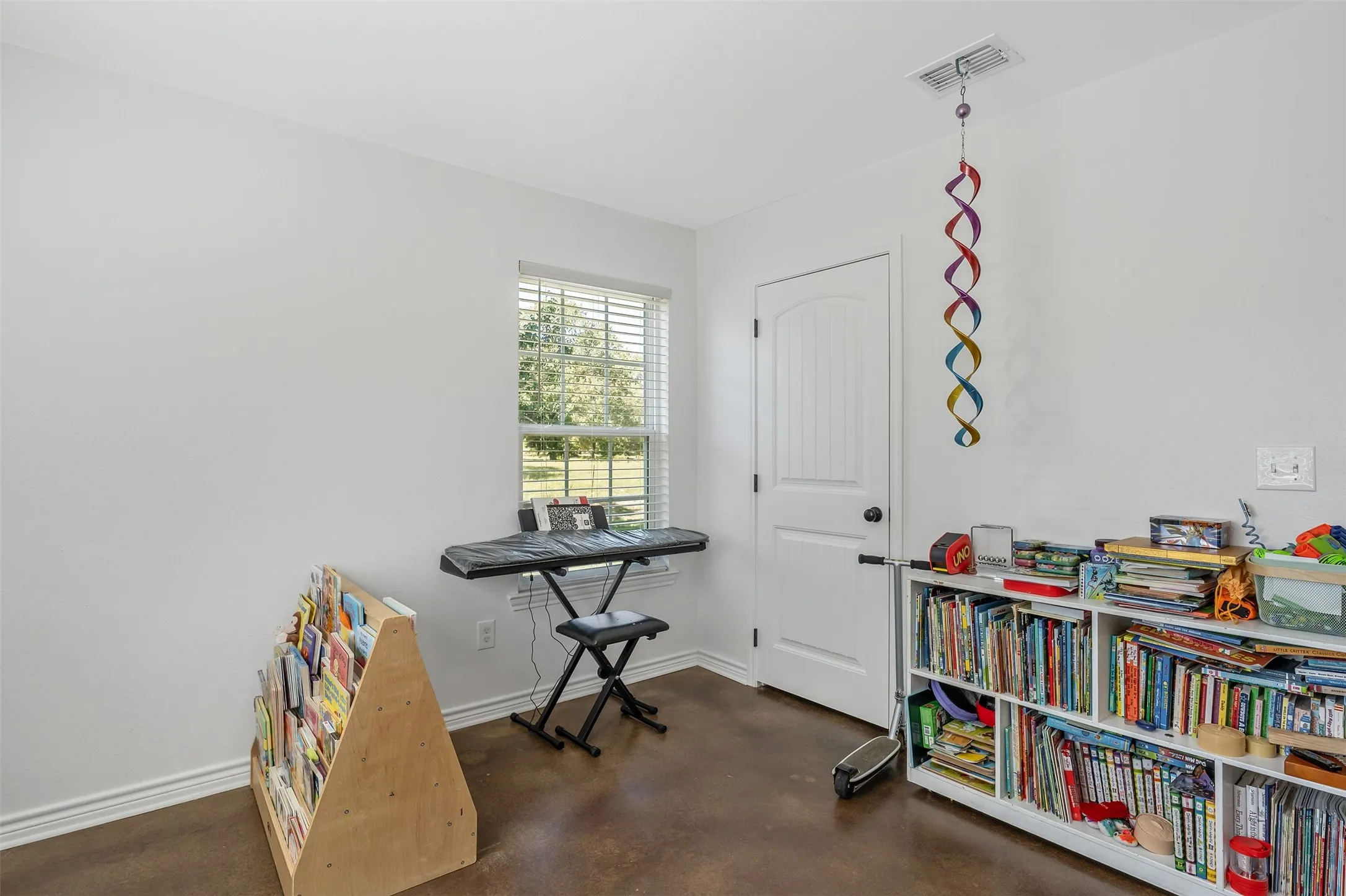 White walls, a single window with blinds, and rich, dark flooring