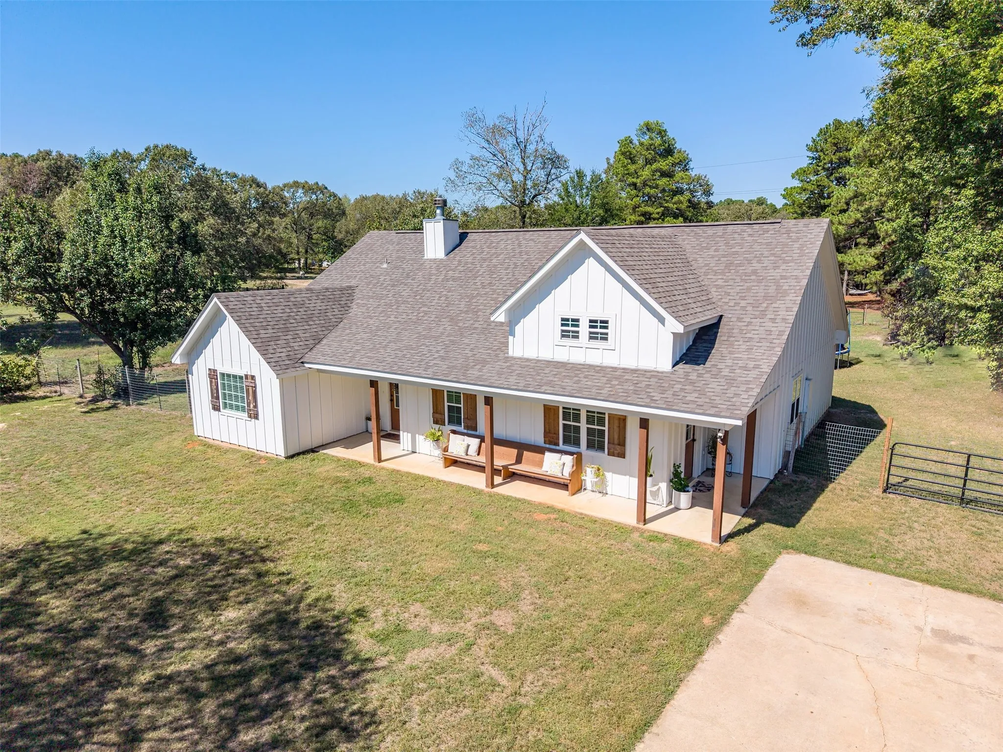 White board and batten exterior with brown shutters, a covered front porch featuring wood-tone columns, and a dormer window