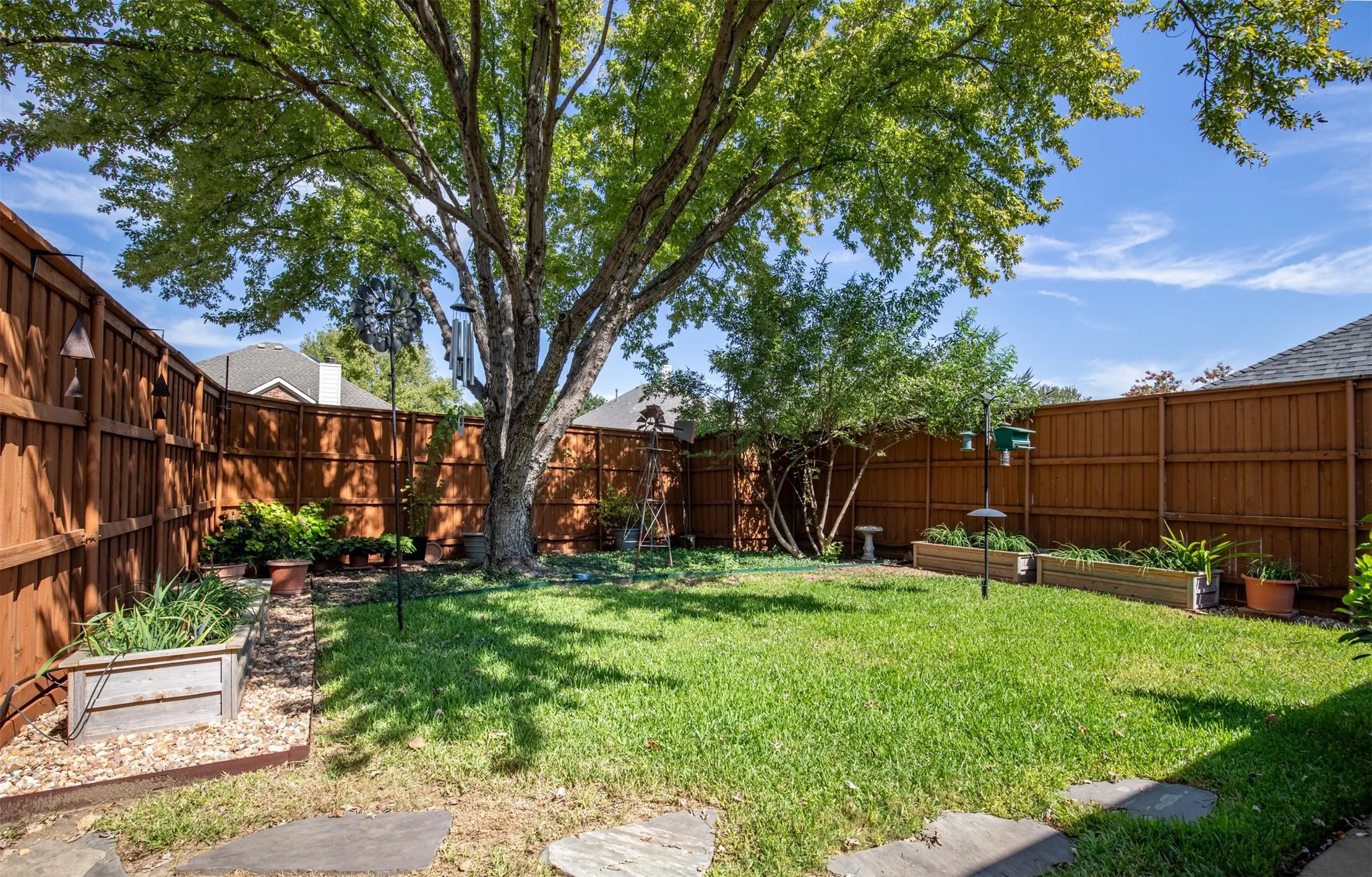 Grassy yard with mature trees and privacy fencing.