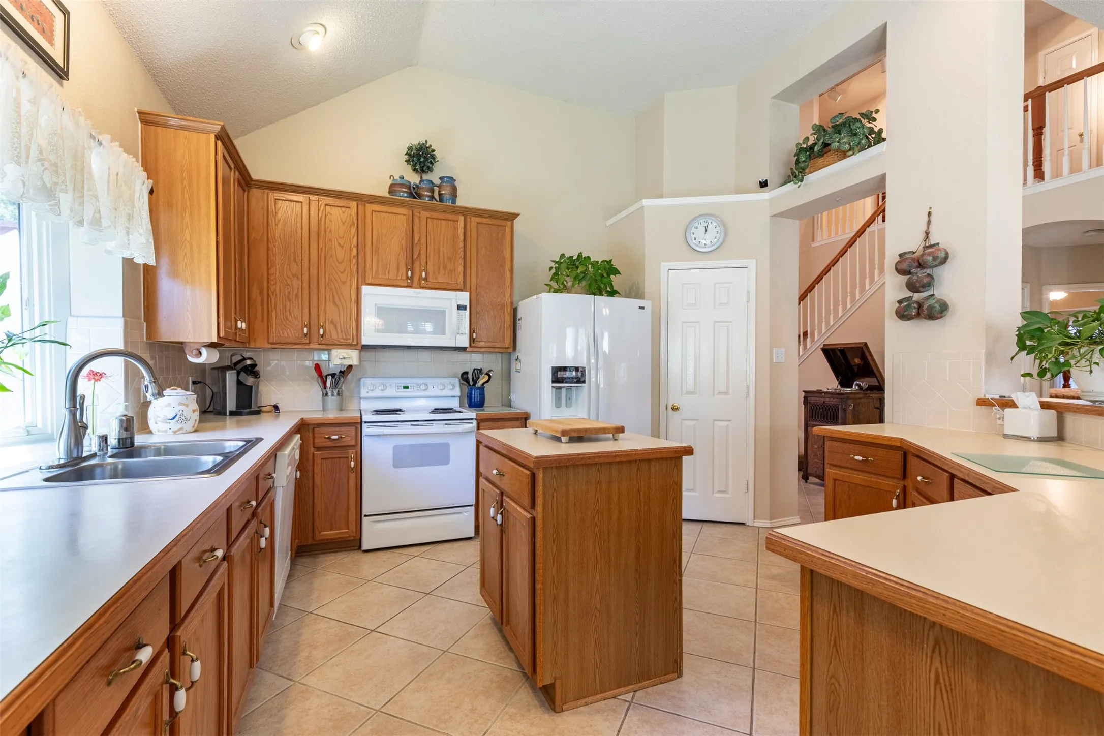 Kitchen with wood cabinetry and prep island with storage.
