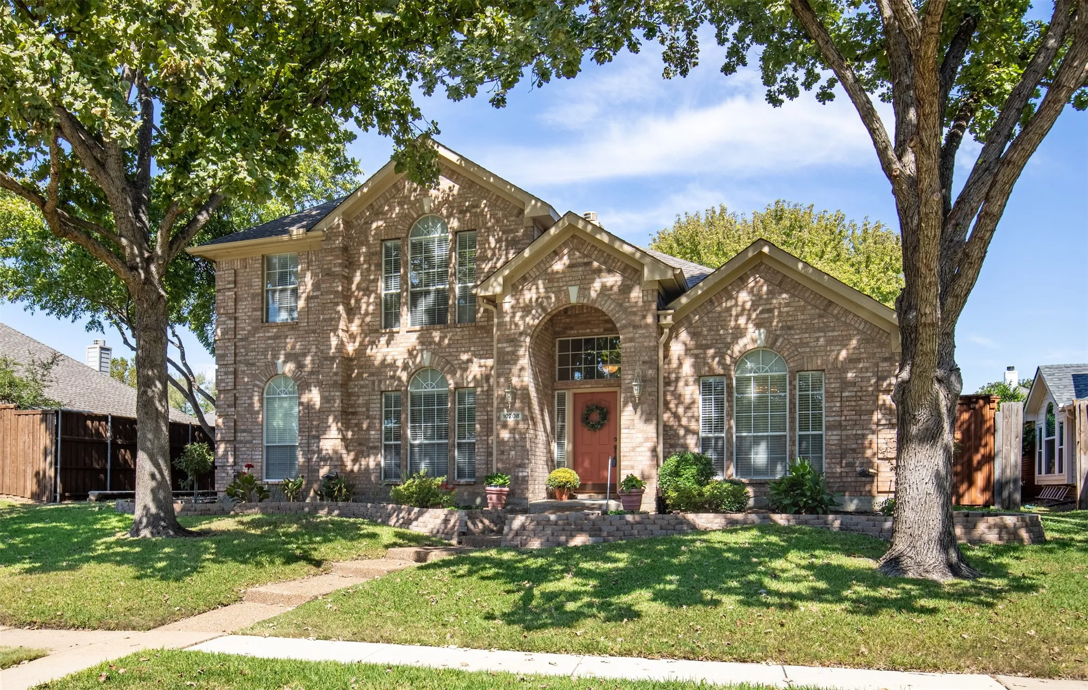 Exterior features shad trees, bordered landscaping, and covered entry.