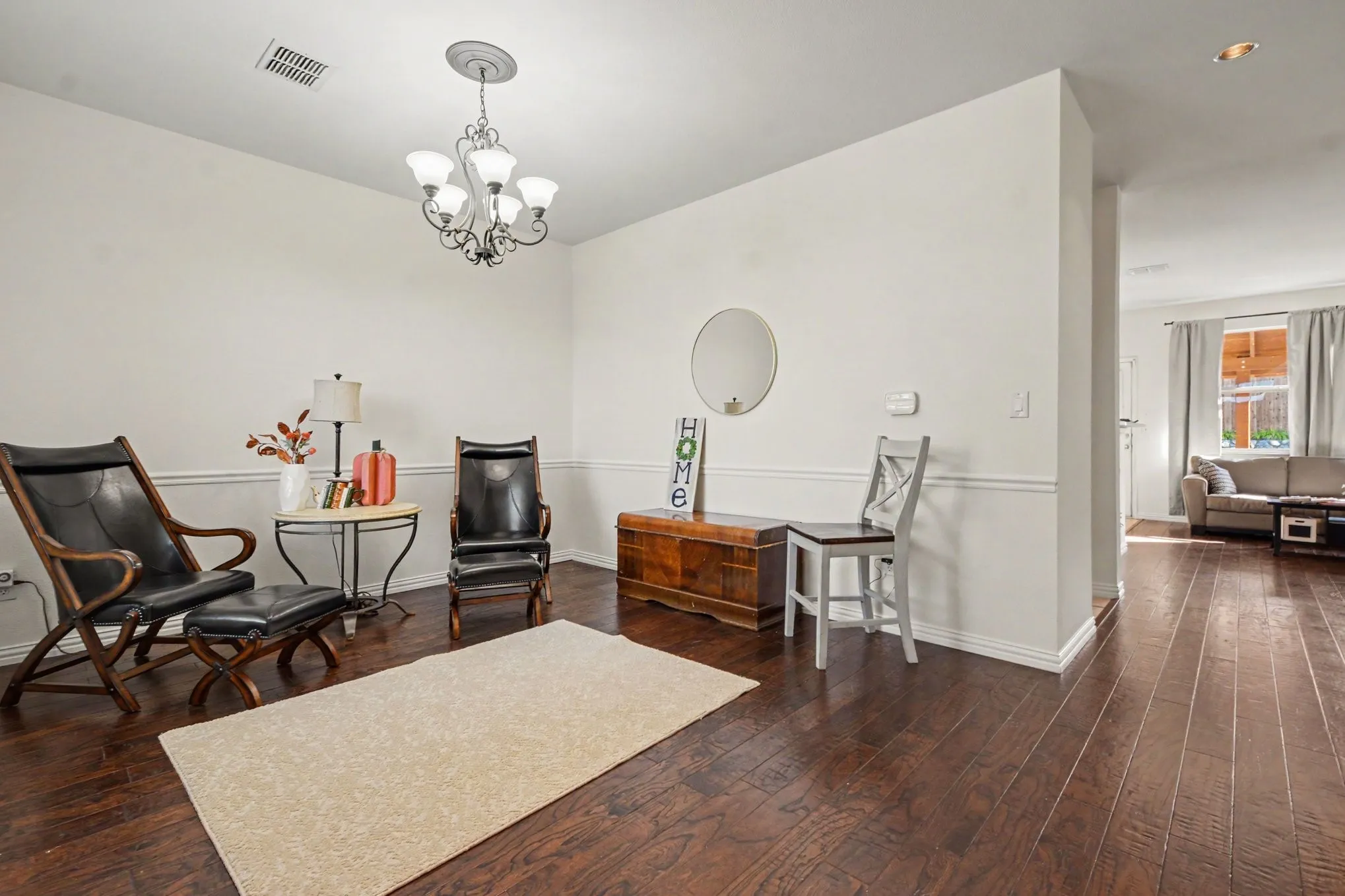Dark wood-finish flooring, white walls with wainscoting, and an ornate chandelier