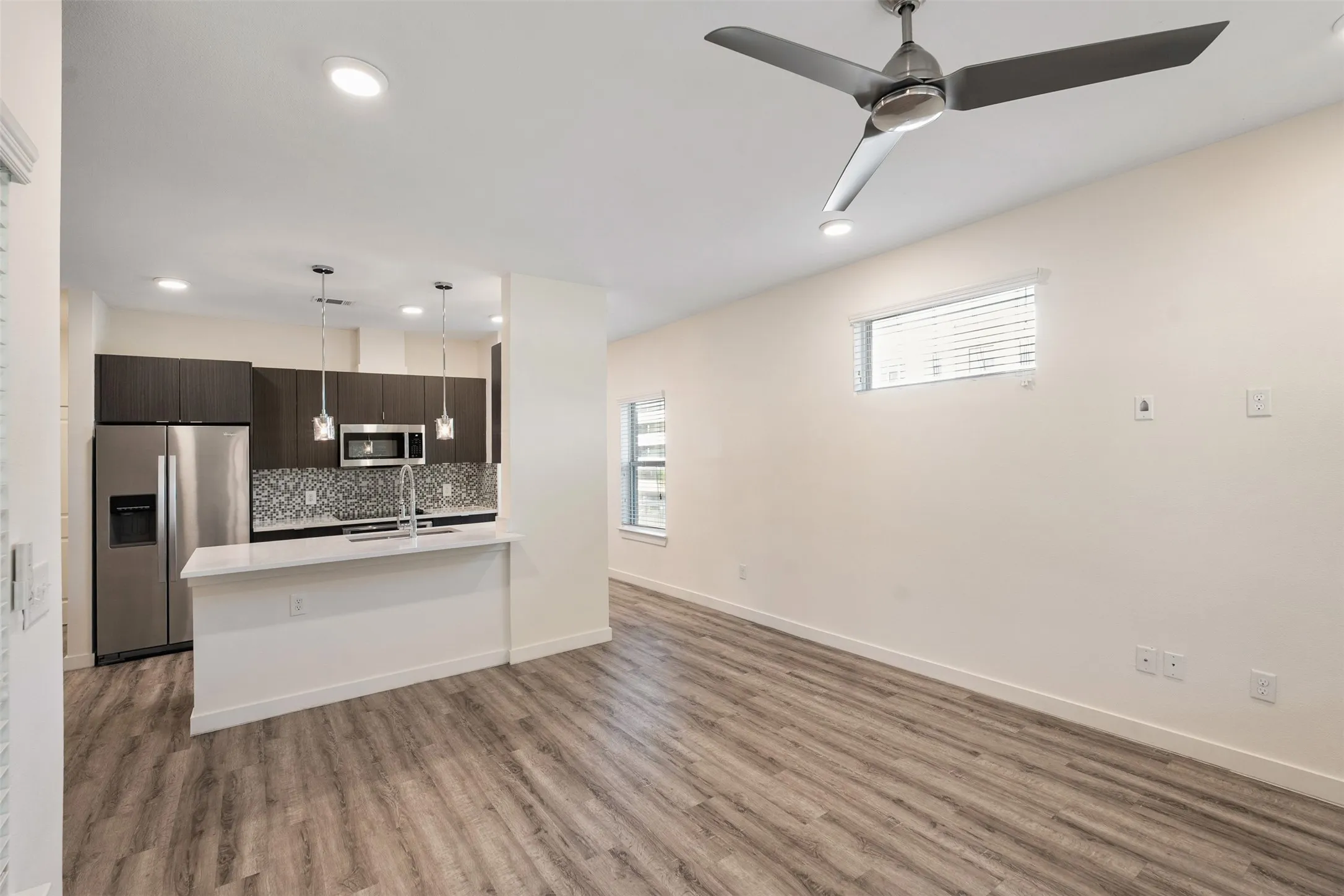 Integrated kitchen with stainless steel appliances, mosaic tile backsplash, and white countertop