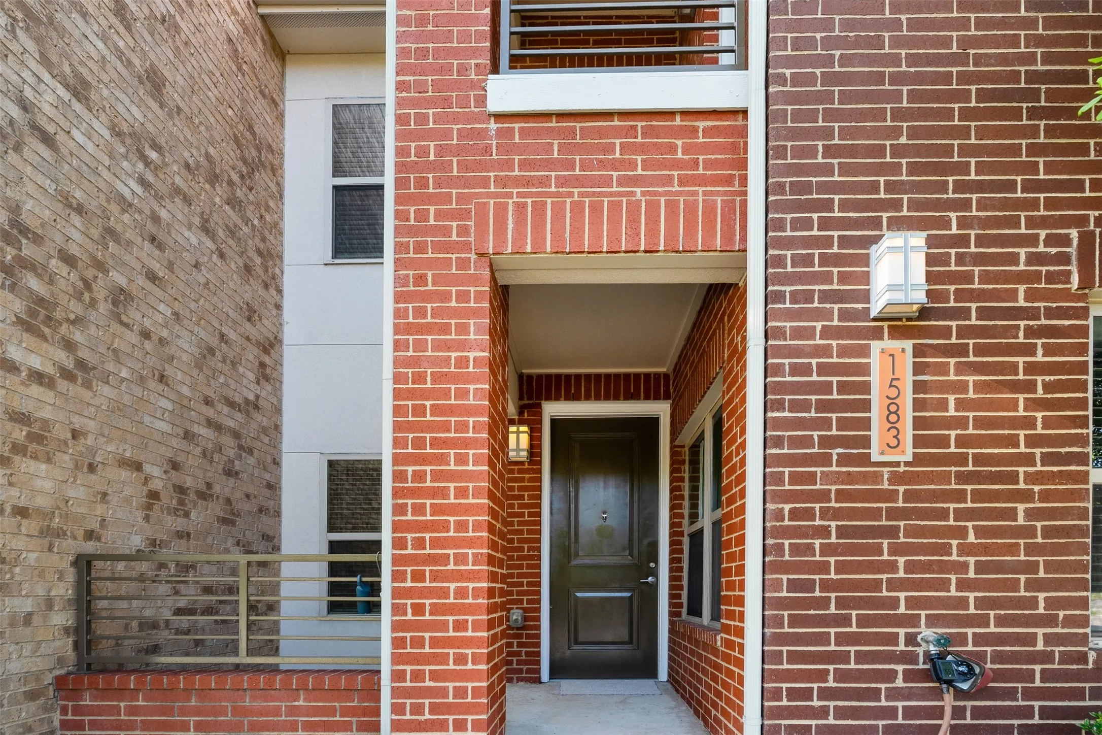 Red brick exterior with a dark wood-finish entry door and a covered entryway