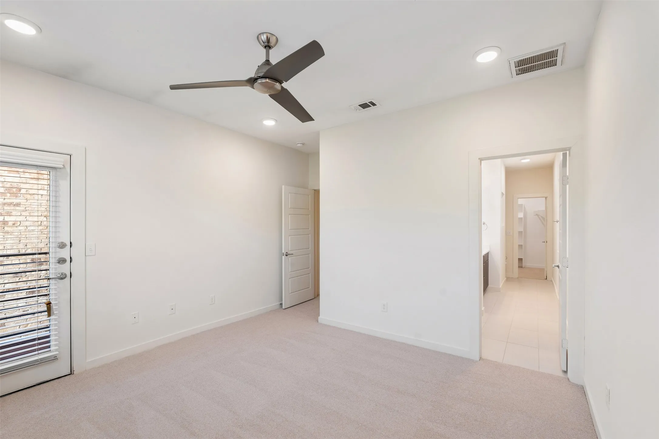 Neutral-toned carpeting, recessed lighting, and a contemporary ceiling fan