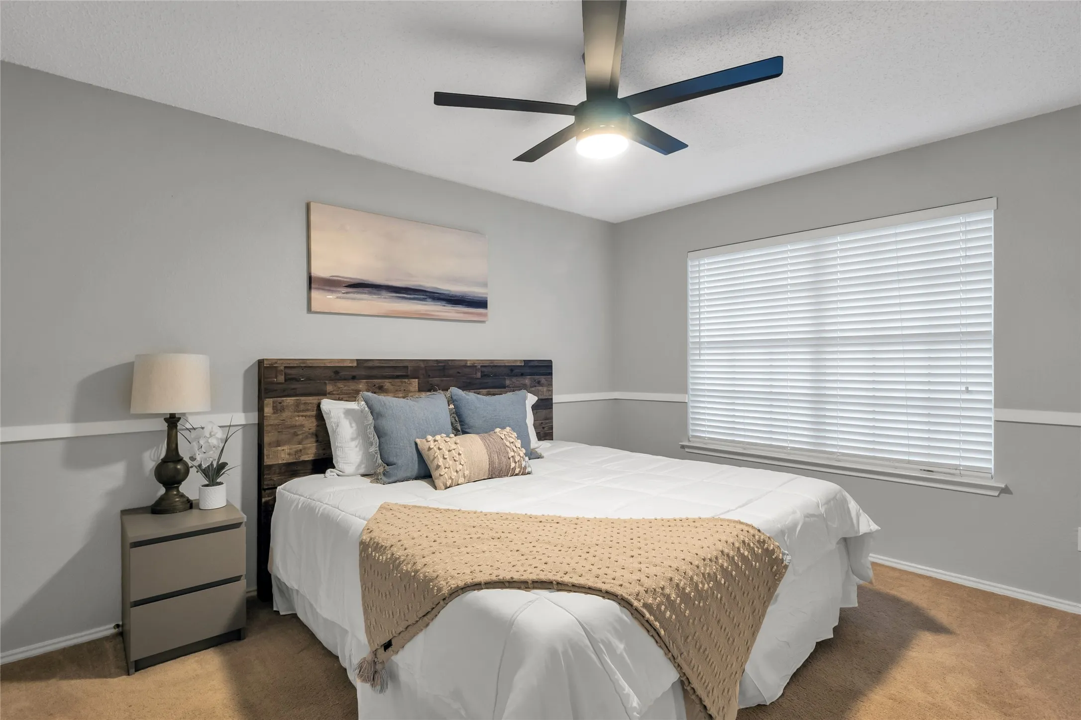 Recessed window with horizontal blinds, wood-finish headboard, and a ceiling fan with integrated lighting