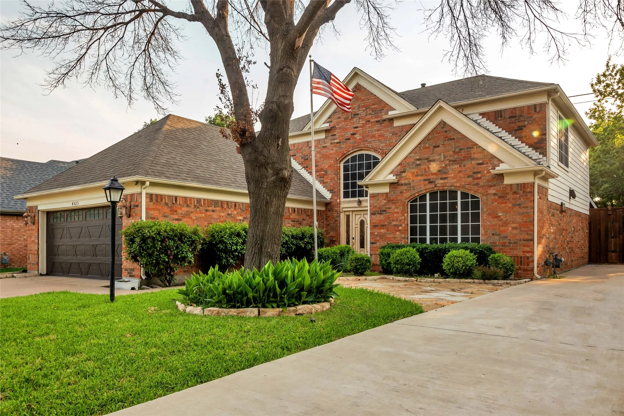 Brick exterior with arched windows, prominent front entry, attached garage, and concrete driveway