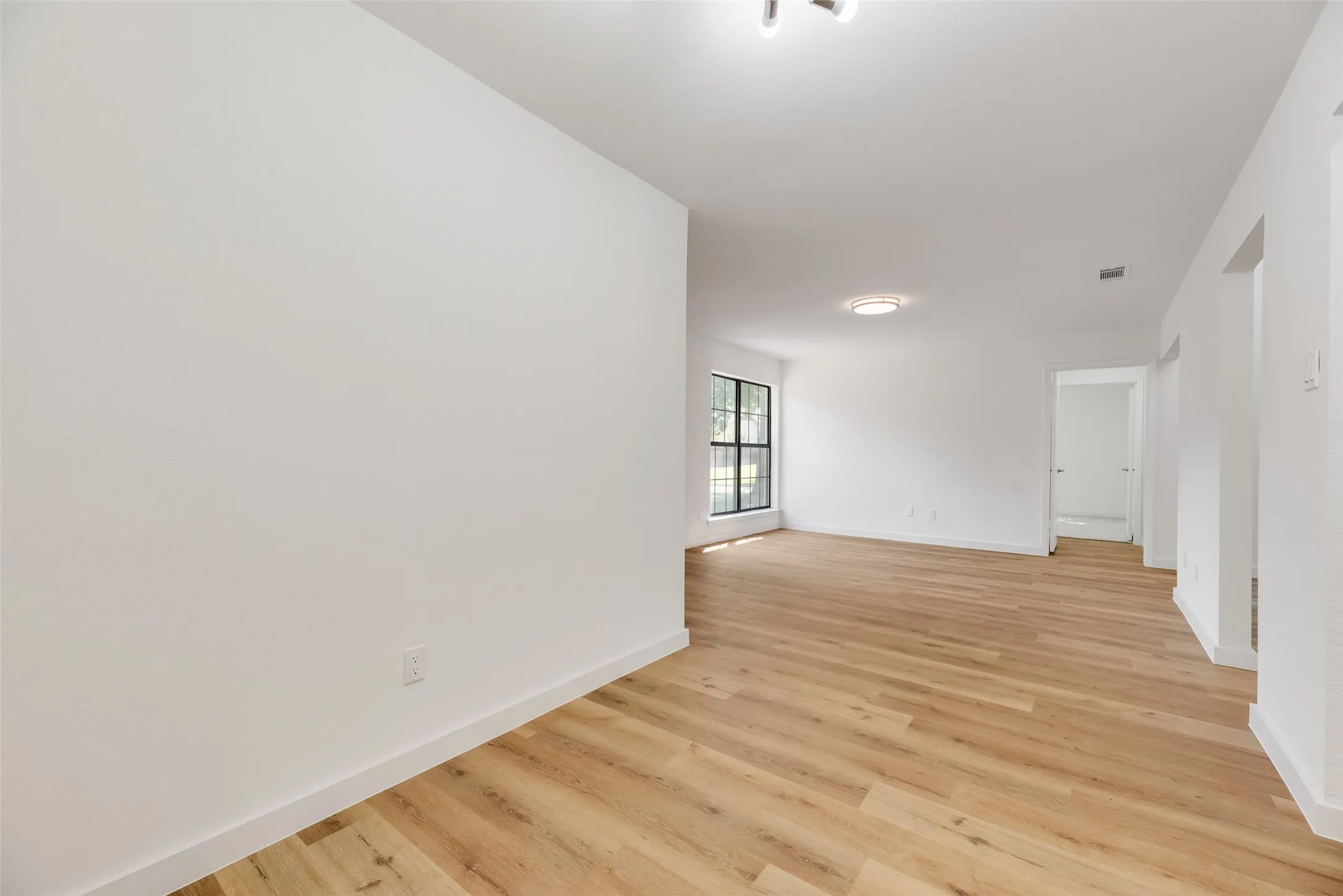 Wood-finish flooring, white walls, and a ceiling-mounted light fixture