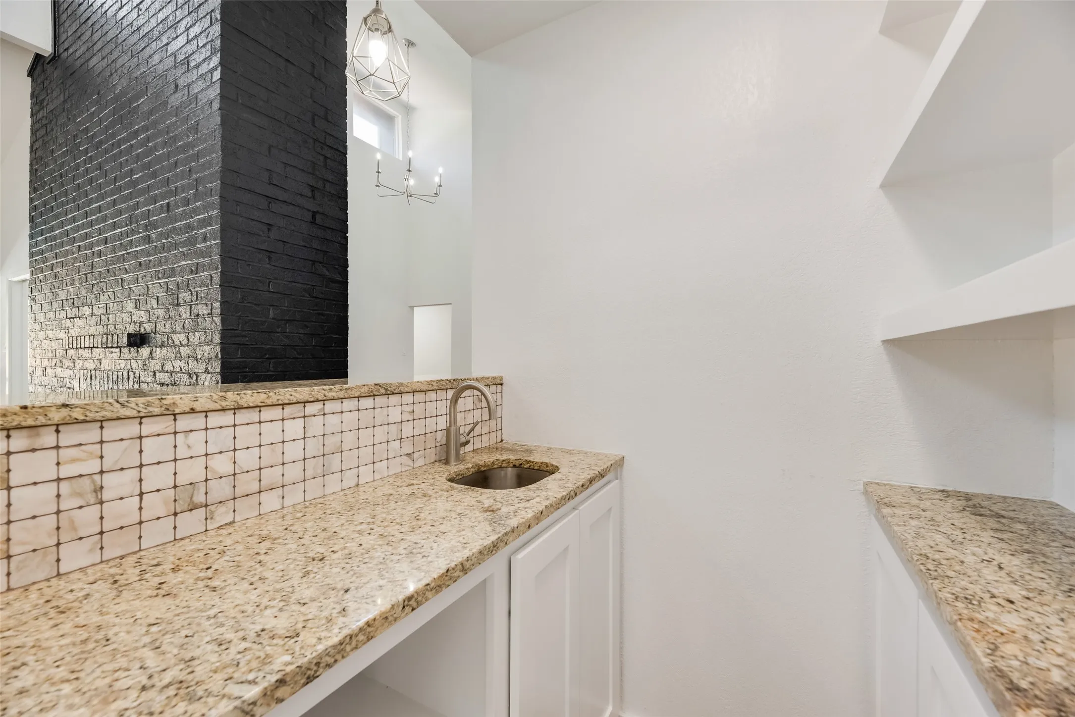 Granite countertops, integrated sink, tiled backsplash, white cabinetry, and open shelving
