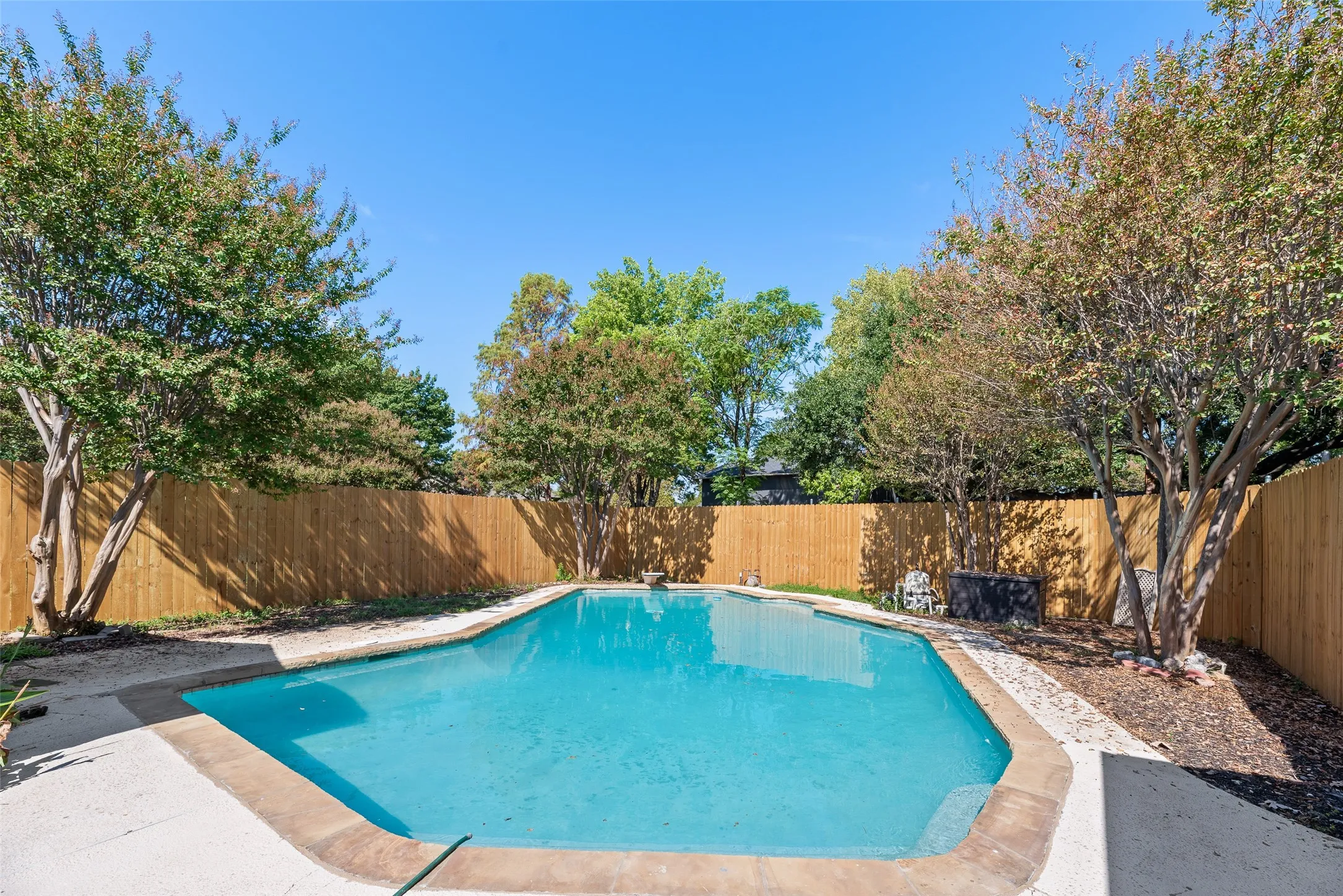 In-ground swimming pool with stone coping and concrete surround