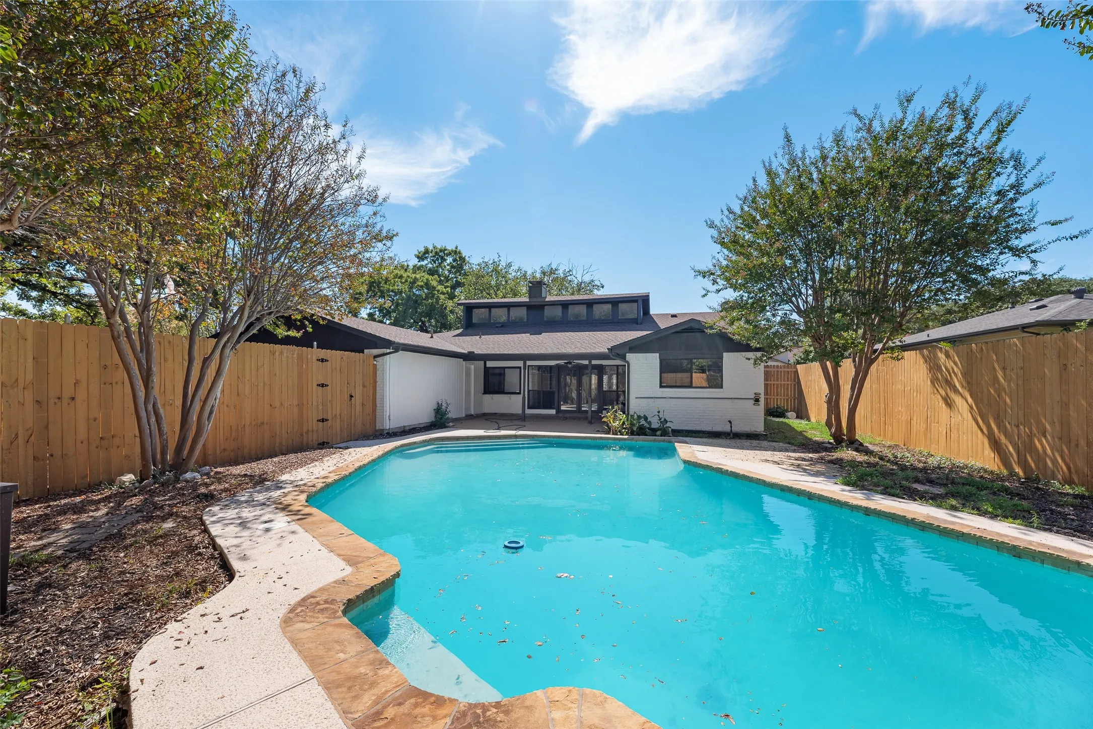 Outdoor swimming pool with patterned concrete and stone coping