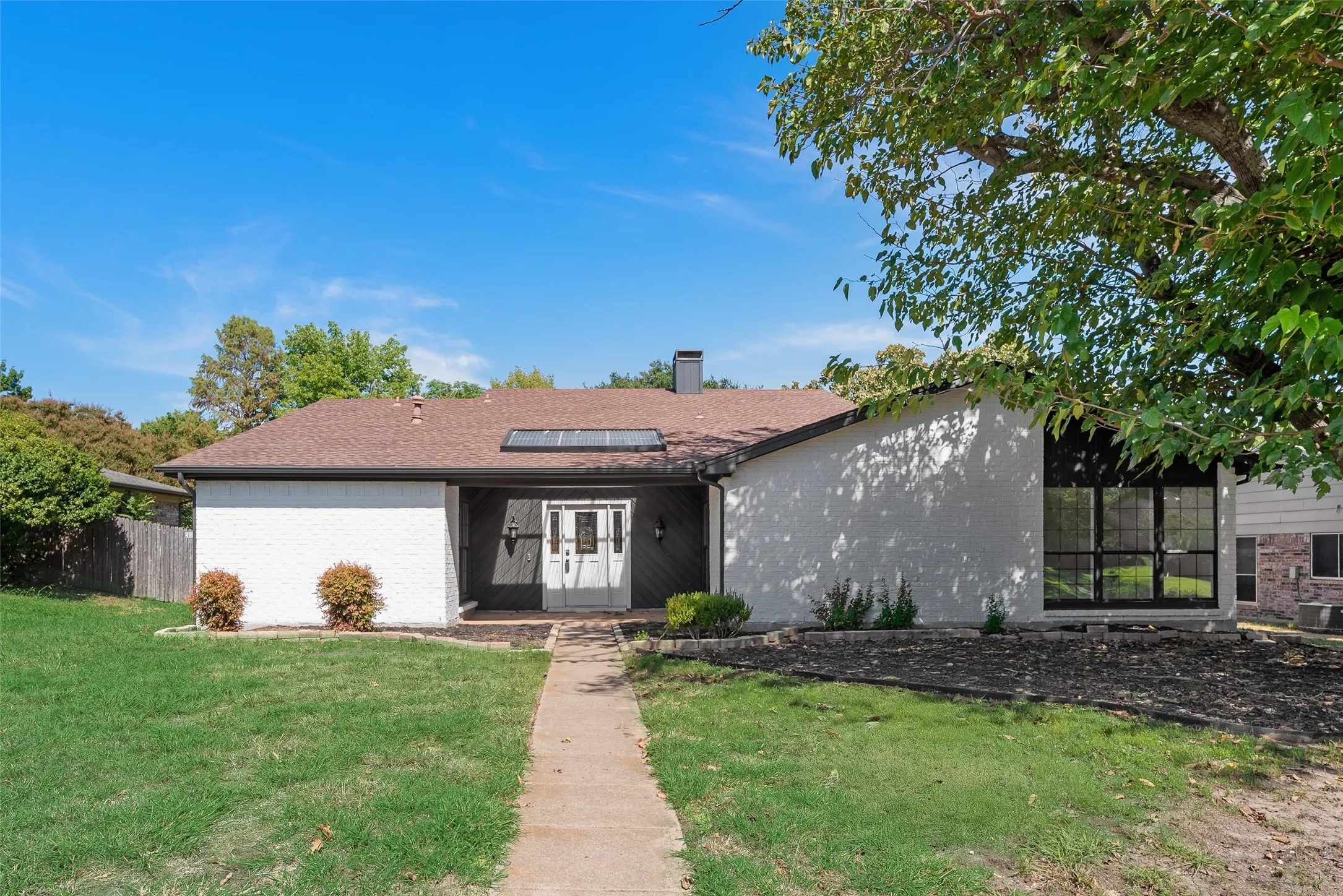 White painted brick exterior with dark trim and a brown shingle roof