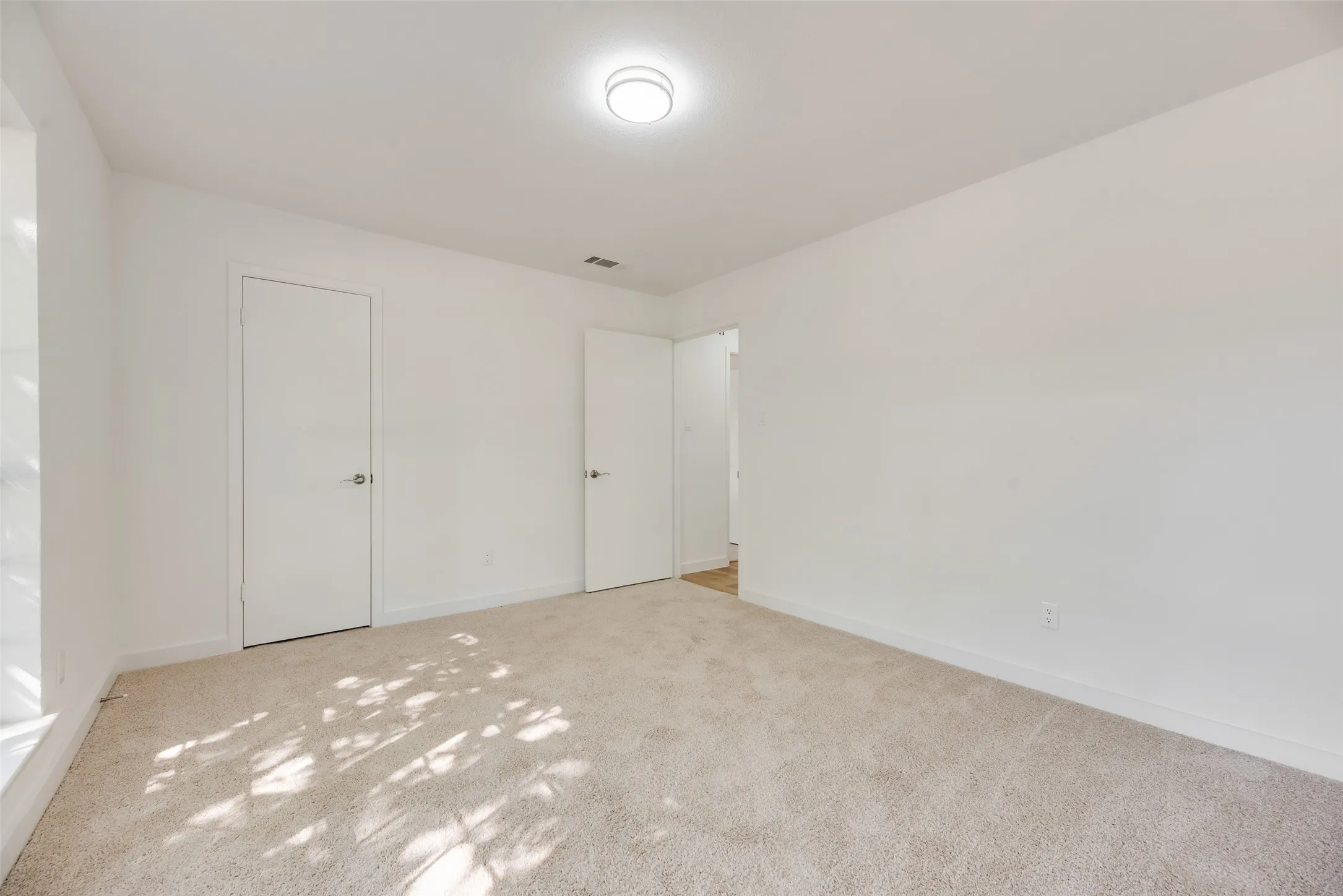 Carpeted flooring, white painted walls, and a flush mount ceiling light