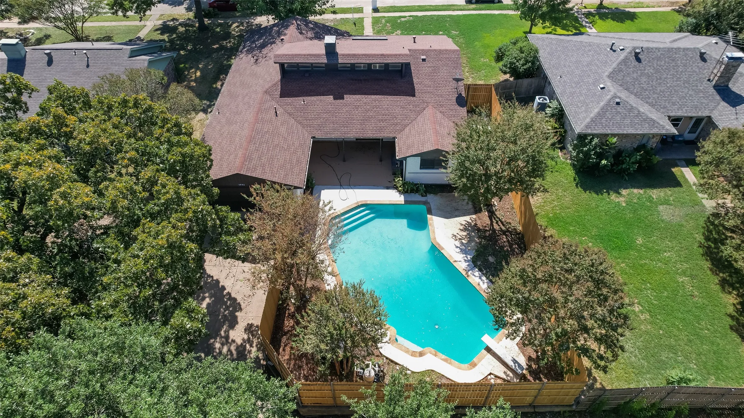 Expansive backyard featuring a kidney-shaped swimming pool, surrounding patio, and wood privacy fencing