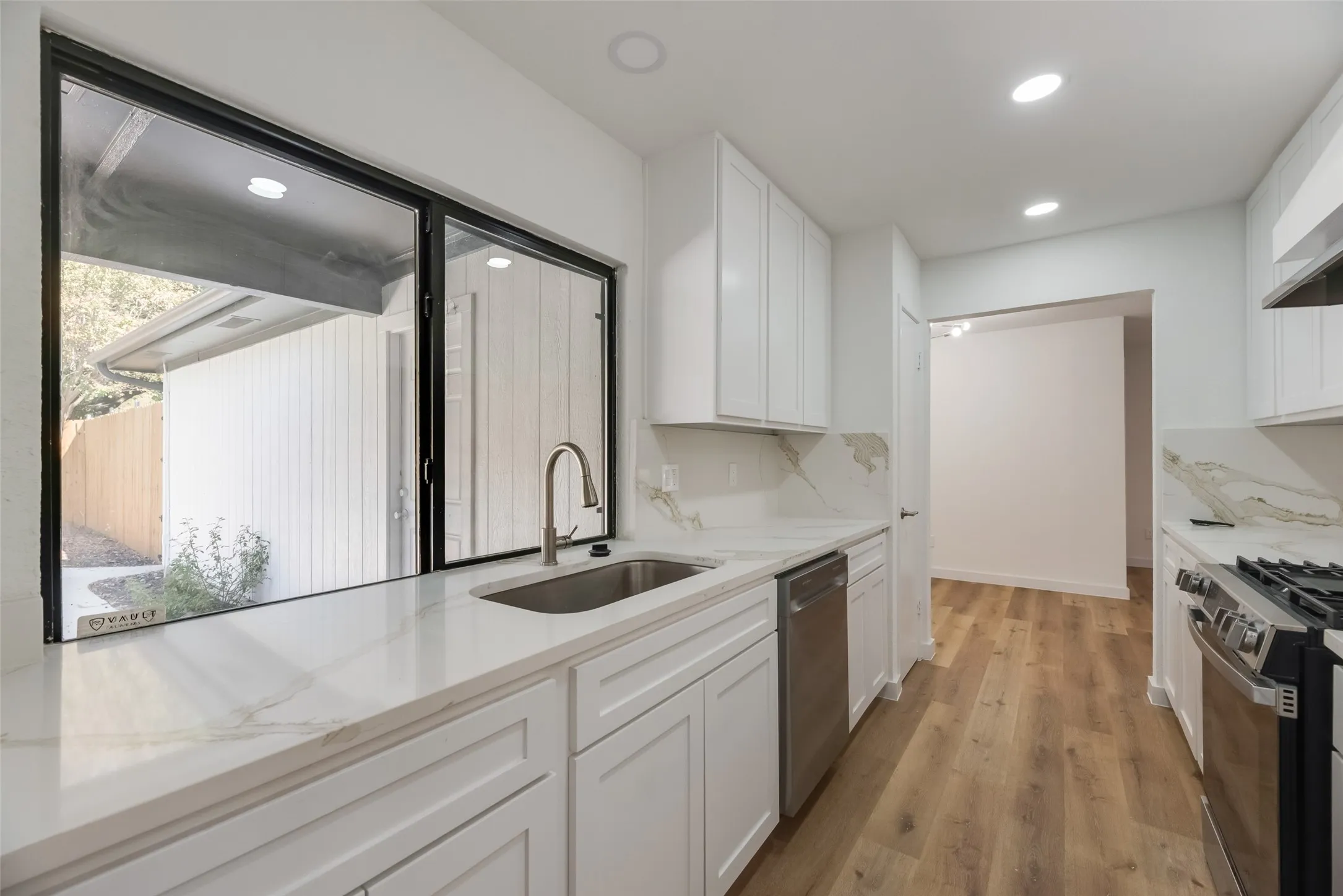 Kitchen featuring white cabinetry, stone countertops, stainless steel appliances, wood-finish flooring, and recessed lighting