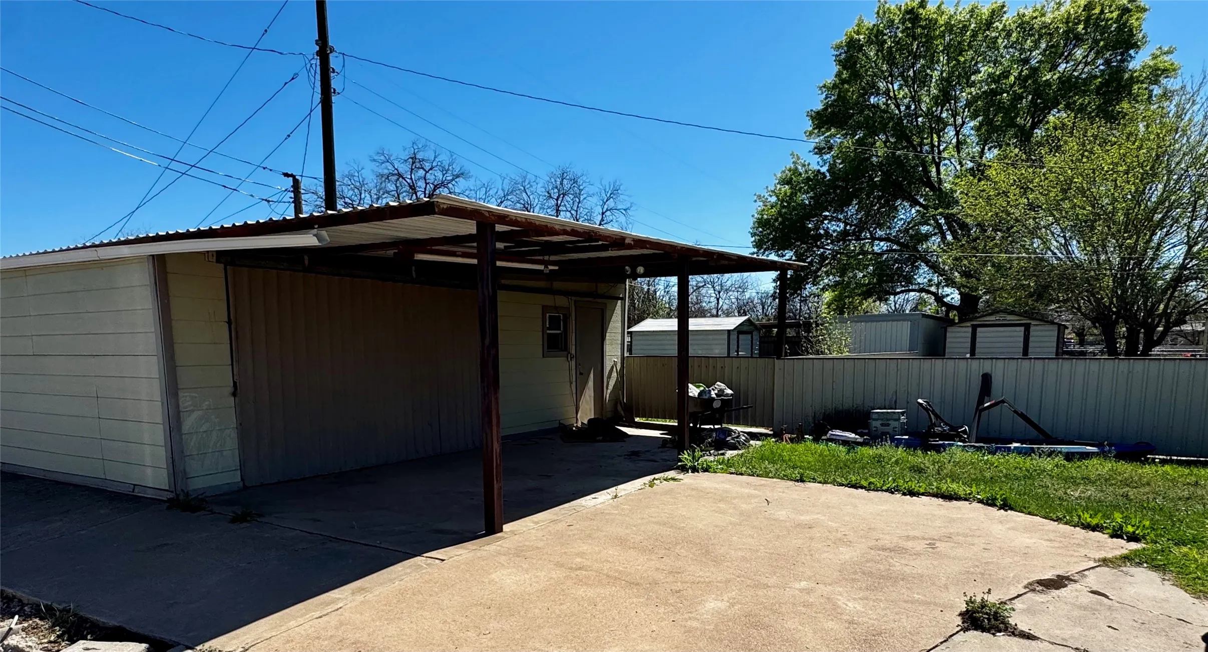 Detached structure with a covered patio area, concrete paving, and a fenced perimeter