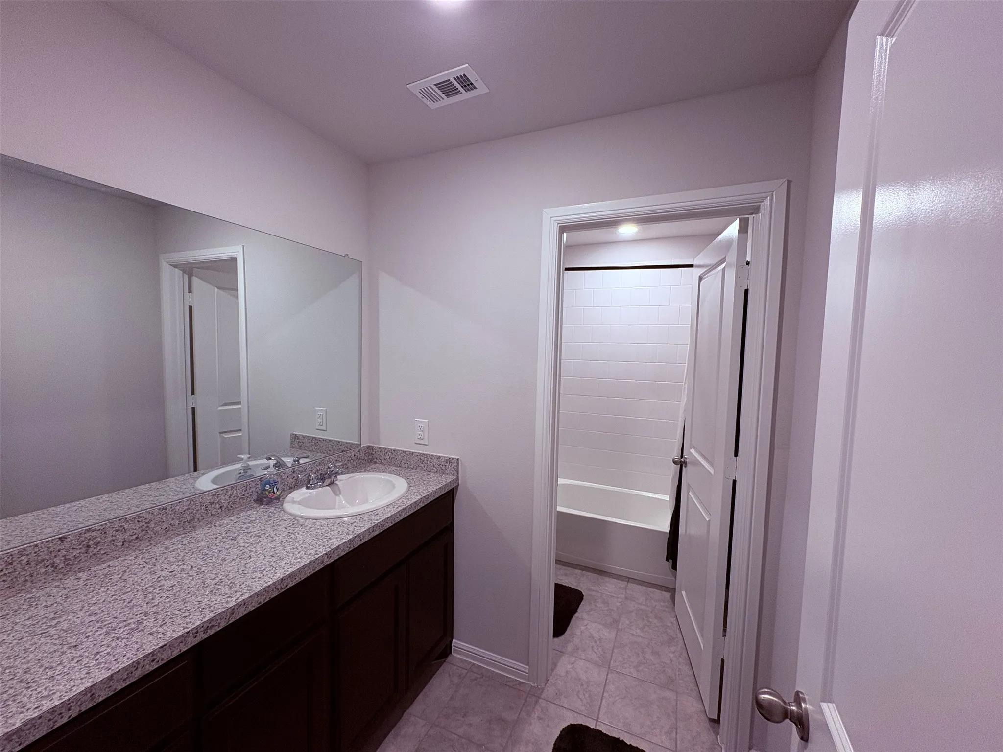 Dual vanity with a speckled countertop, undermount sinks, and dark wood-finish cabinetry