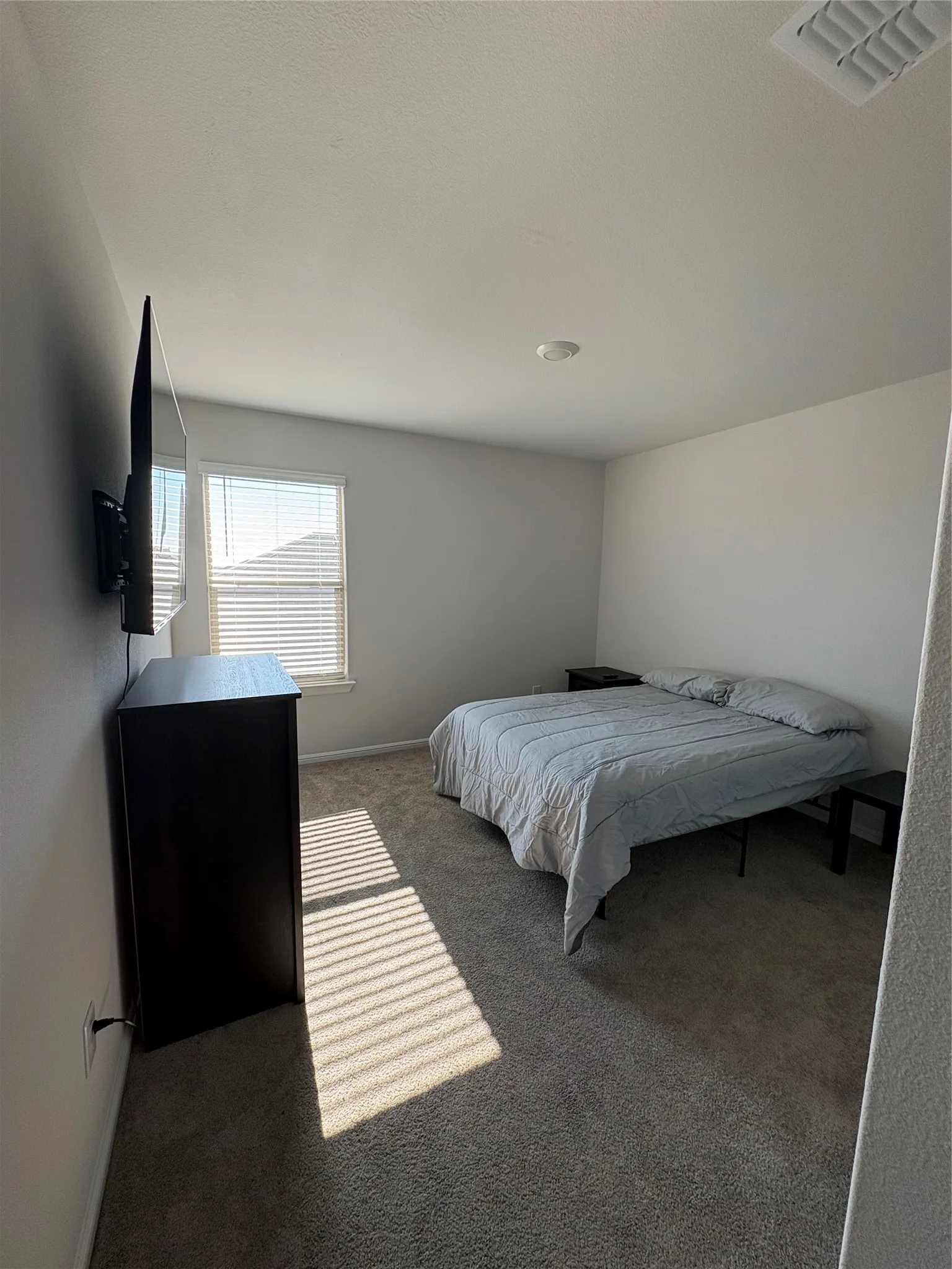 Recessed ceiling light, wall-to-wall carpeting, and a window with blinds