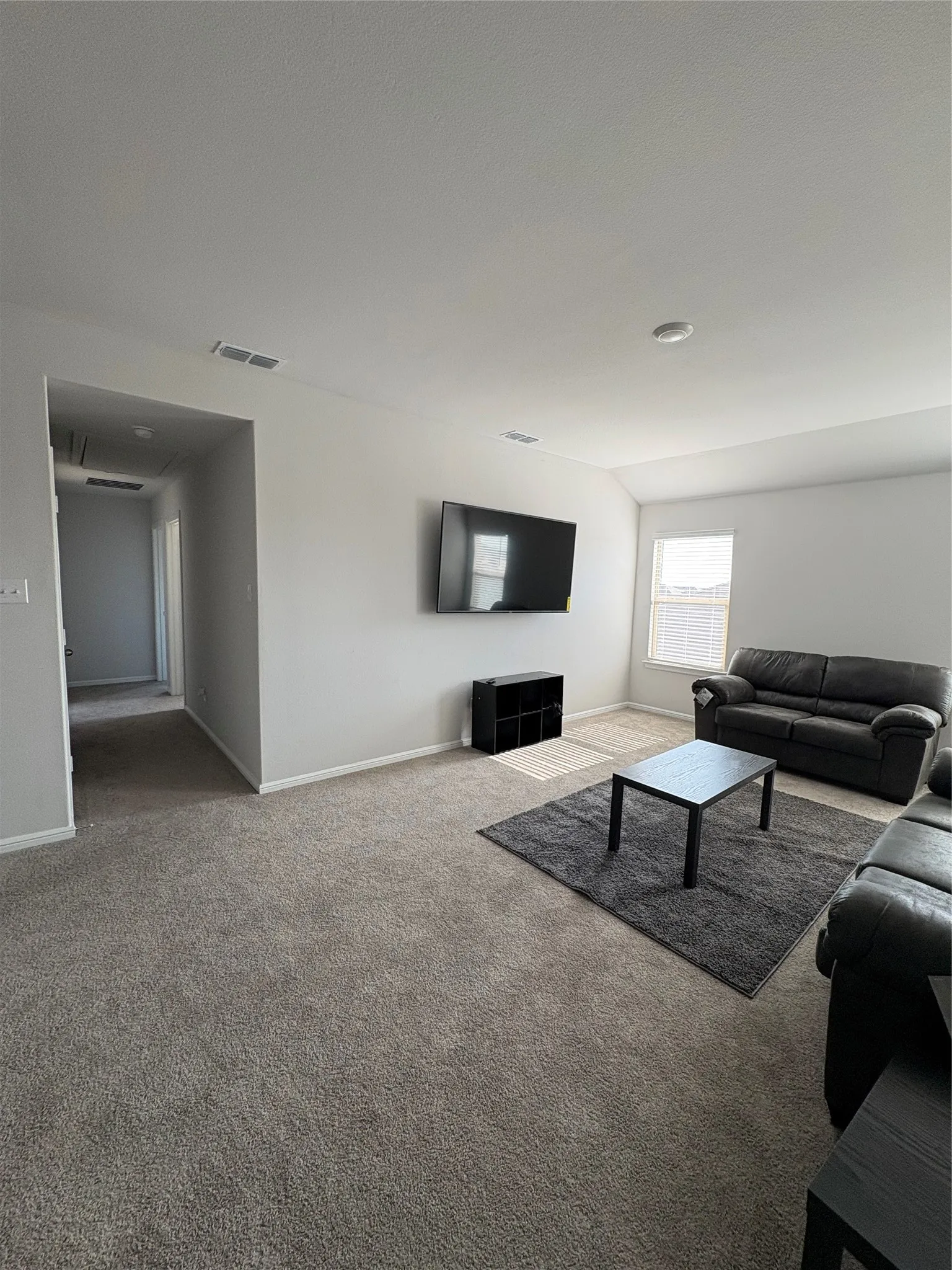 Recessed lighting illuminates the carpeted living area with light gray walls