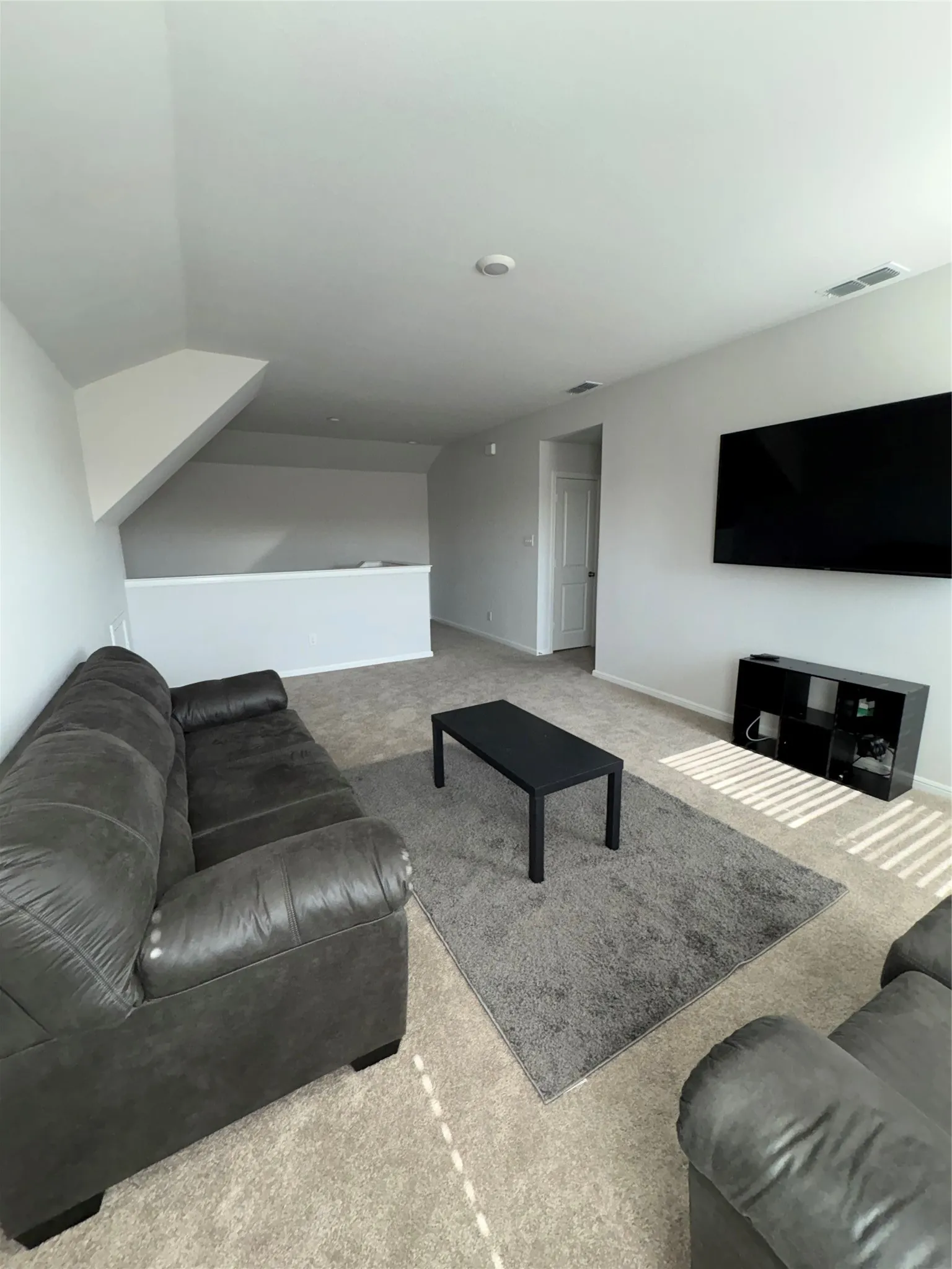Carpeted flooring, vaulted ceiling, and white wall finishes