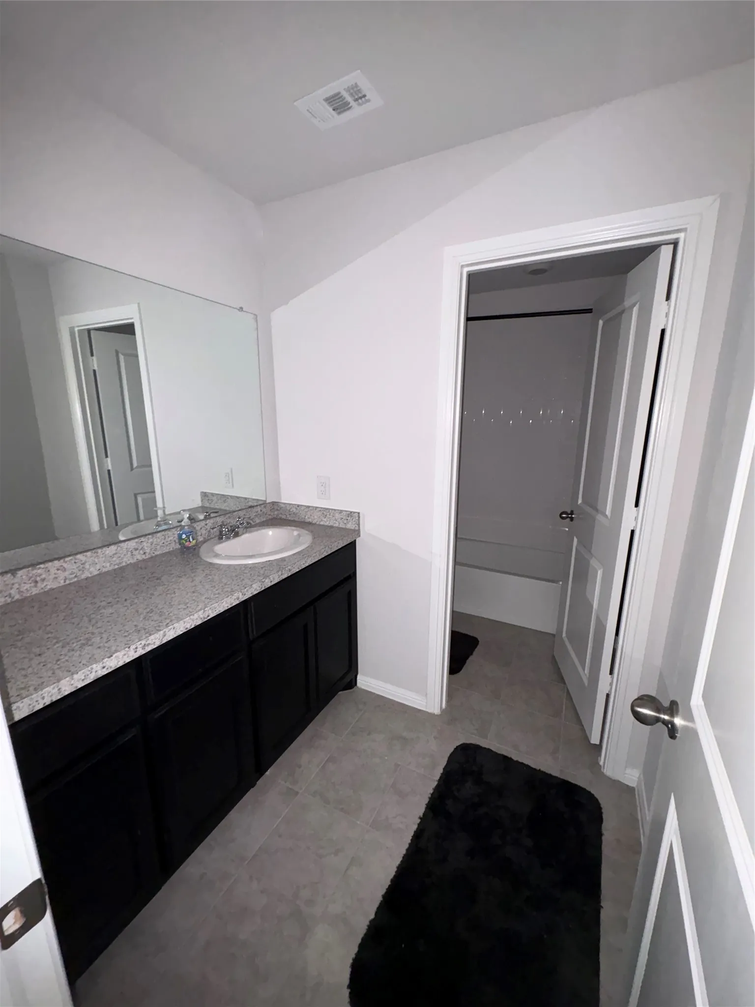 Vanity with a solid surface countertop, integrated sink, and dark cabinet storage