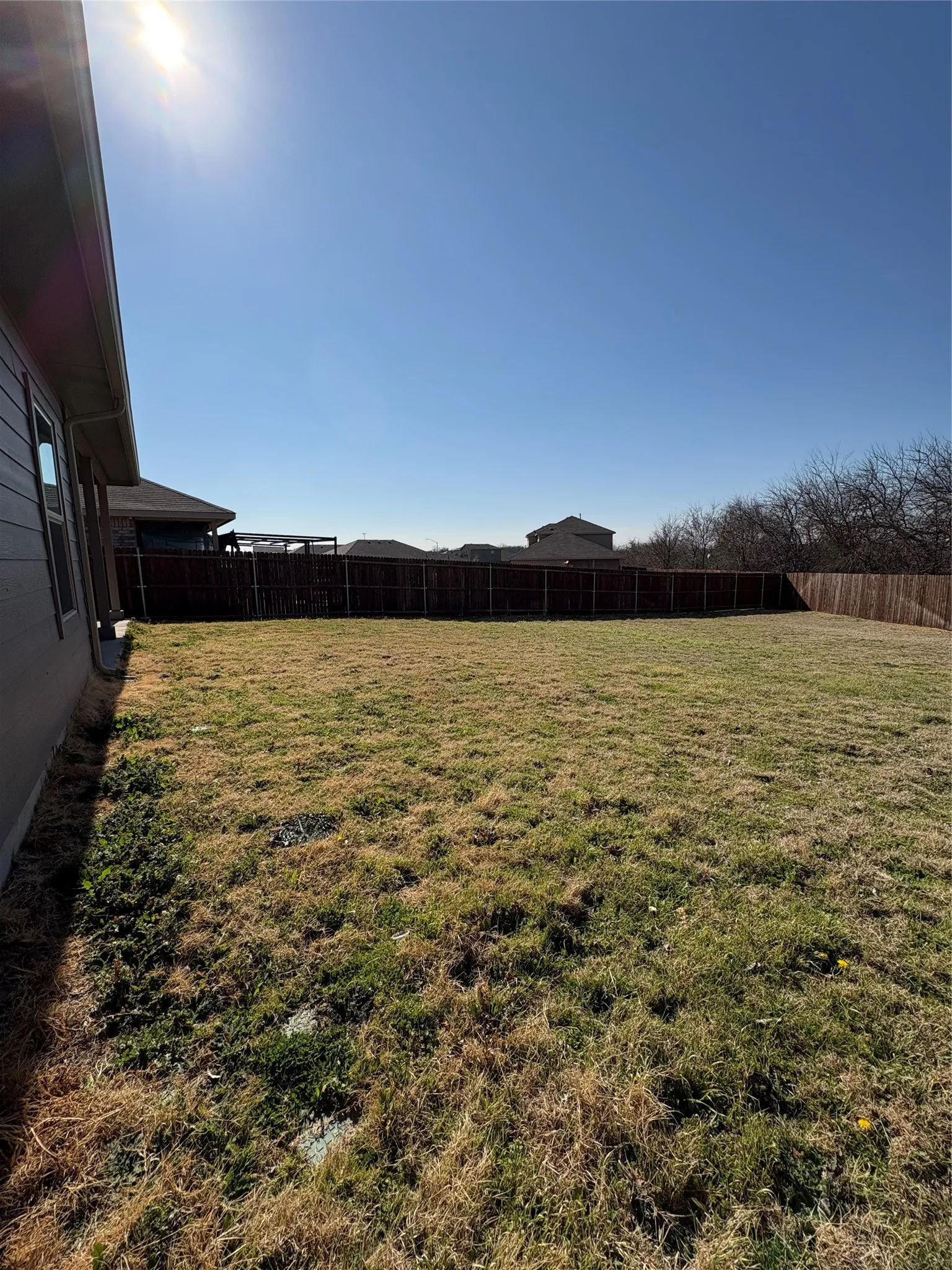 Expansive backyard featuring a privacy fence and a building exterior with horizontal siding