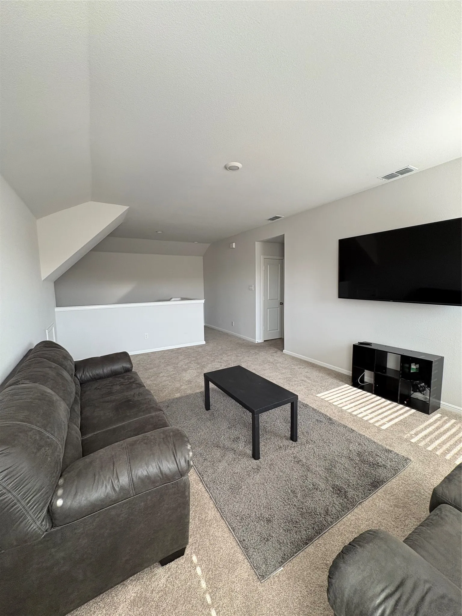 Spacious carpeted area with a half-wall partition and a white paneled door
