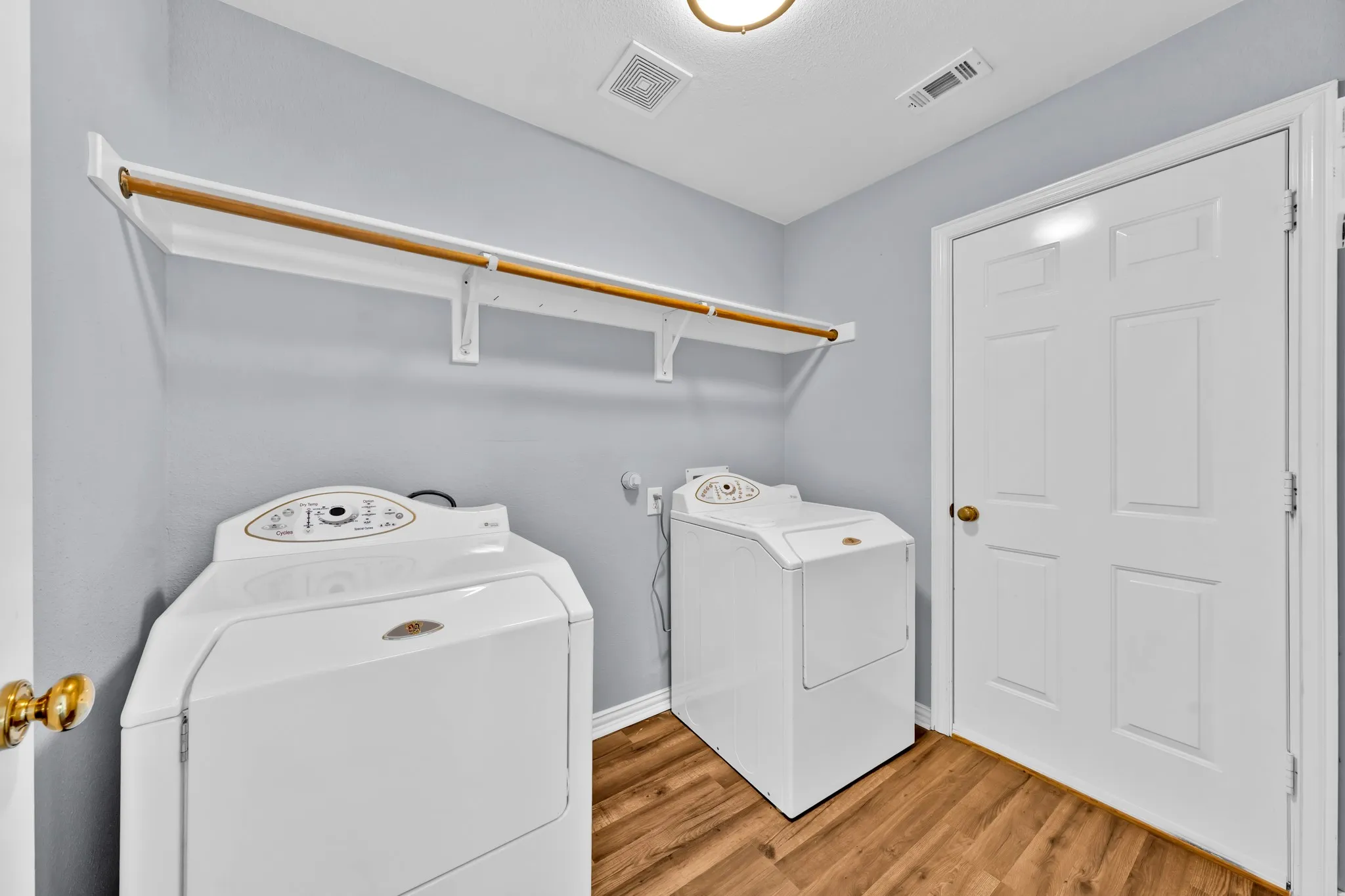 Dedicated utility area featuring wood-finish flooring and a neutral color palette