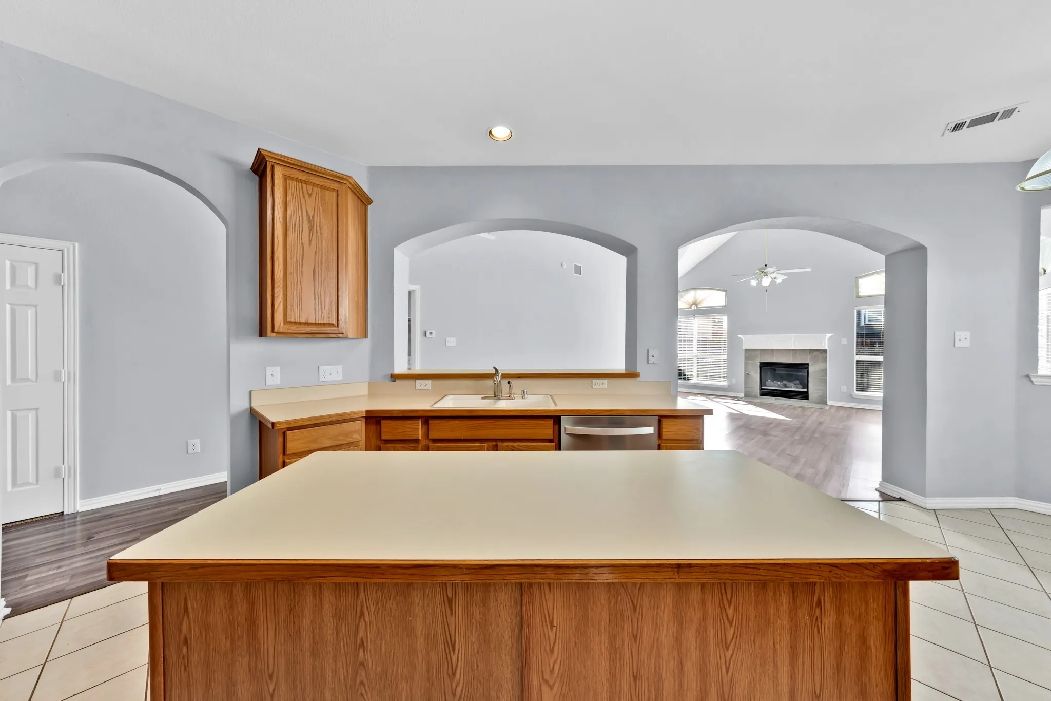 Kitchen island with countertop seating, wood-finish cabinetry, stainless steel sink, and integrated dishwasher