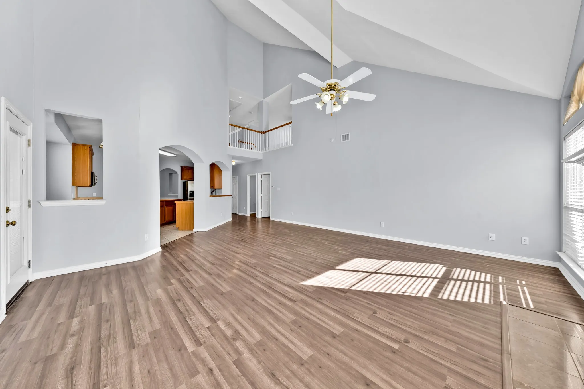Vaulted ceilings, wood-finish flooring, architectural archways, and an upper-level railing
