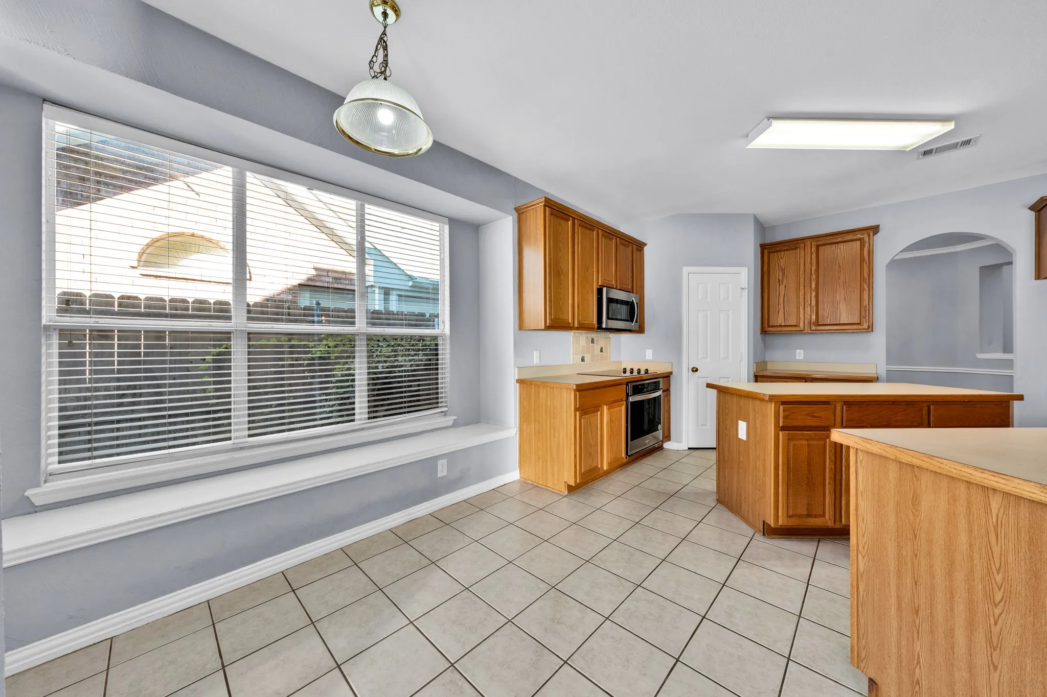 Kitchen featuring wood cabinetry, tile flooring, built-in microwave, and oven