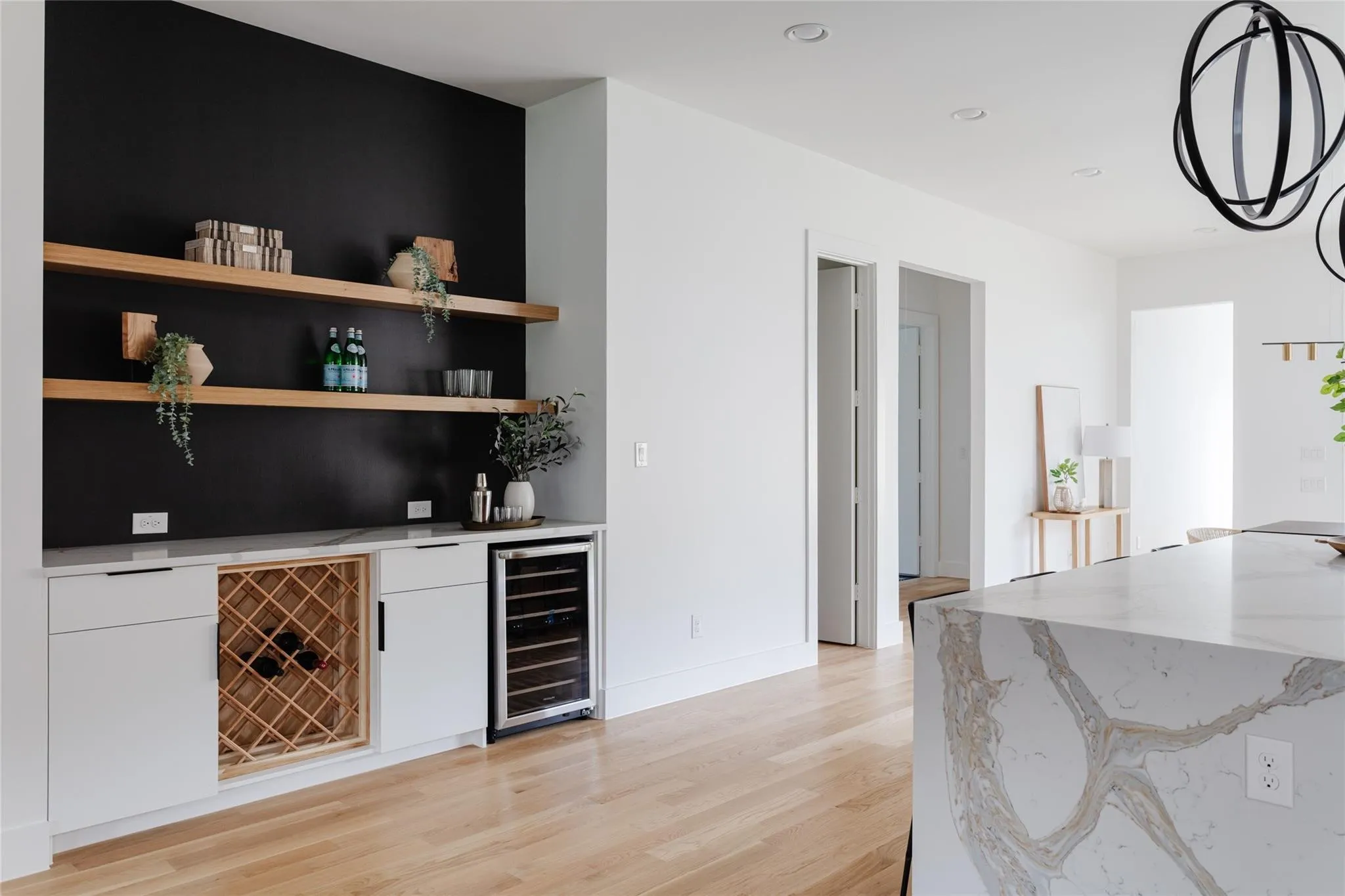 Built-in beverage bar with open shelving, recessed lighting, and wood-finish flooring