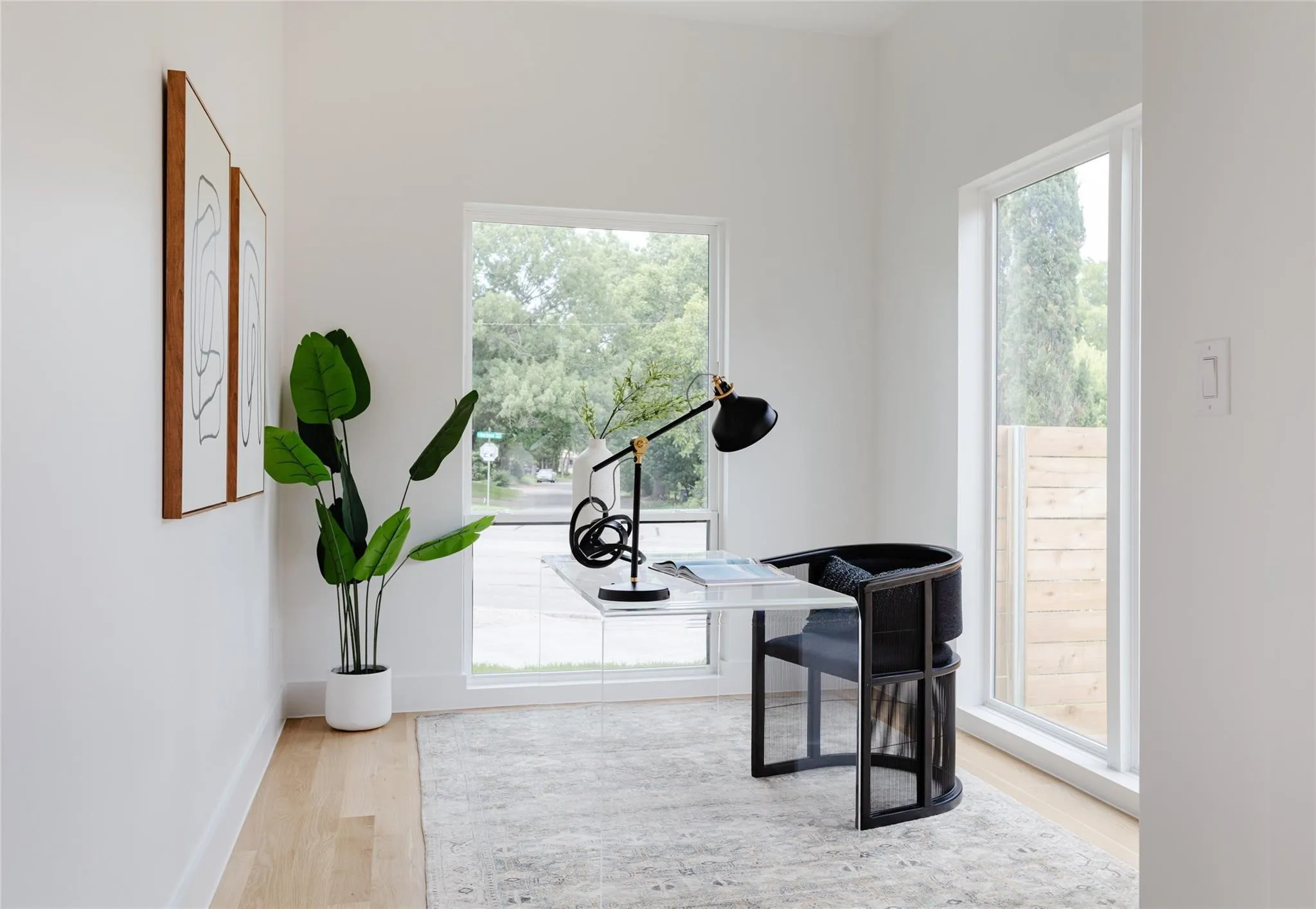 Light-filled interior space featuring wood-finish flooring, white walls, and multiple large windows