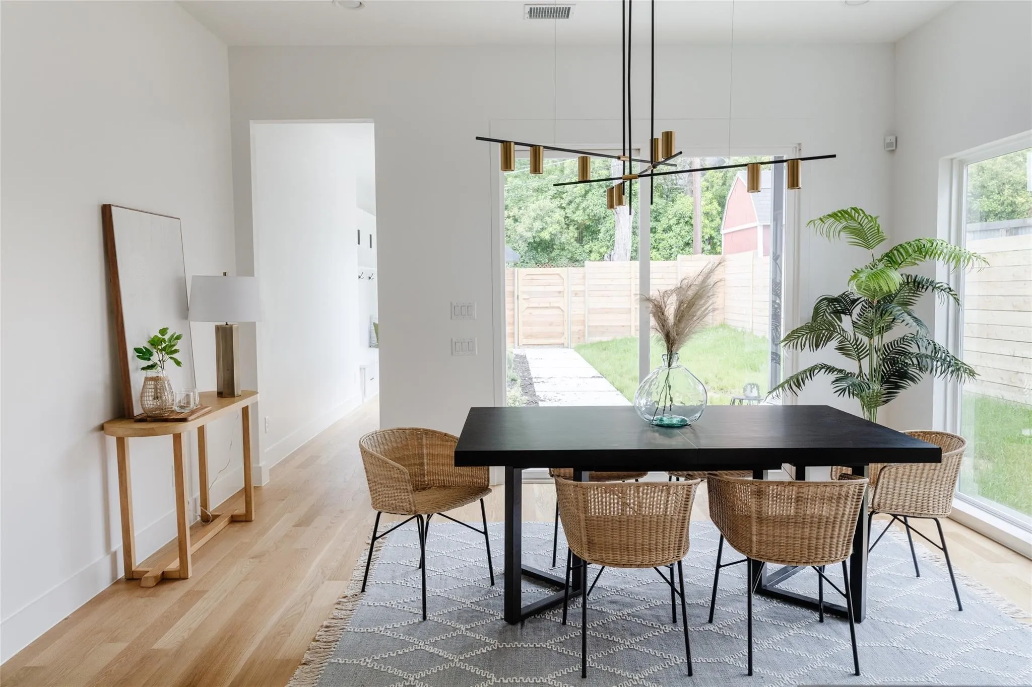Hardwood flooring, white painted walls, large glass windows, and a modern linear chandelier