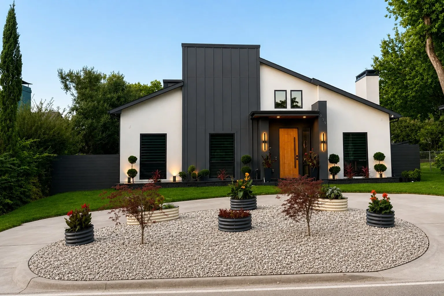 Modern exterior featuring a white stucco finish with dark vertical siding accents, a natural wood-tone entry door, and an aggregate circular driveway with a gravel landscape island